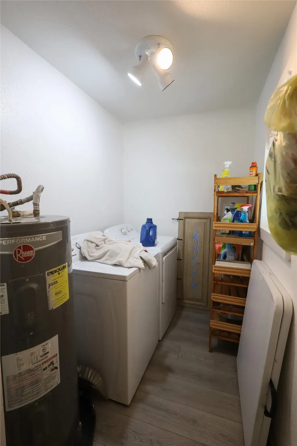 Clothes washing area with water heater, dark wood-type flooring, and independent washer and dryer