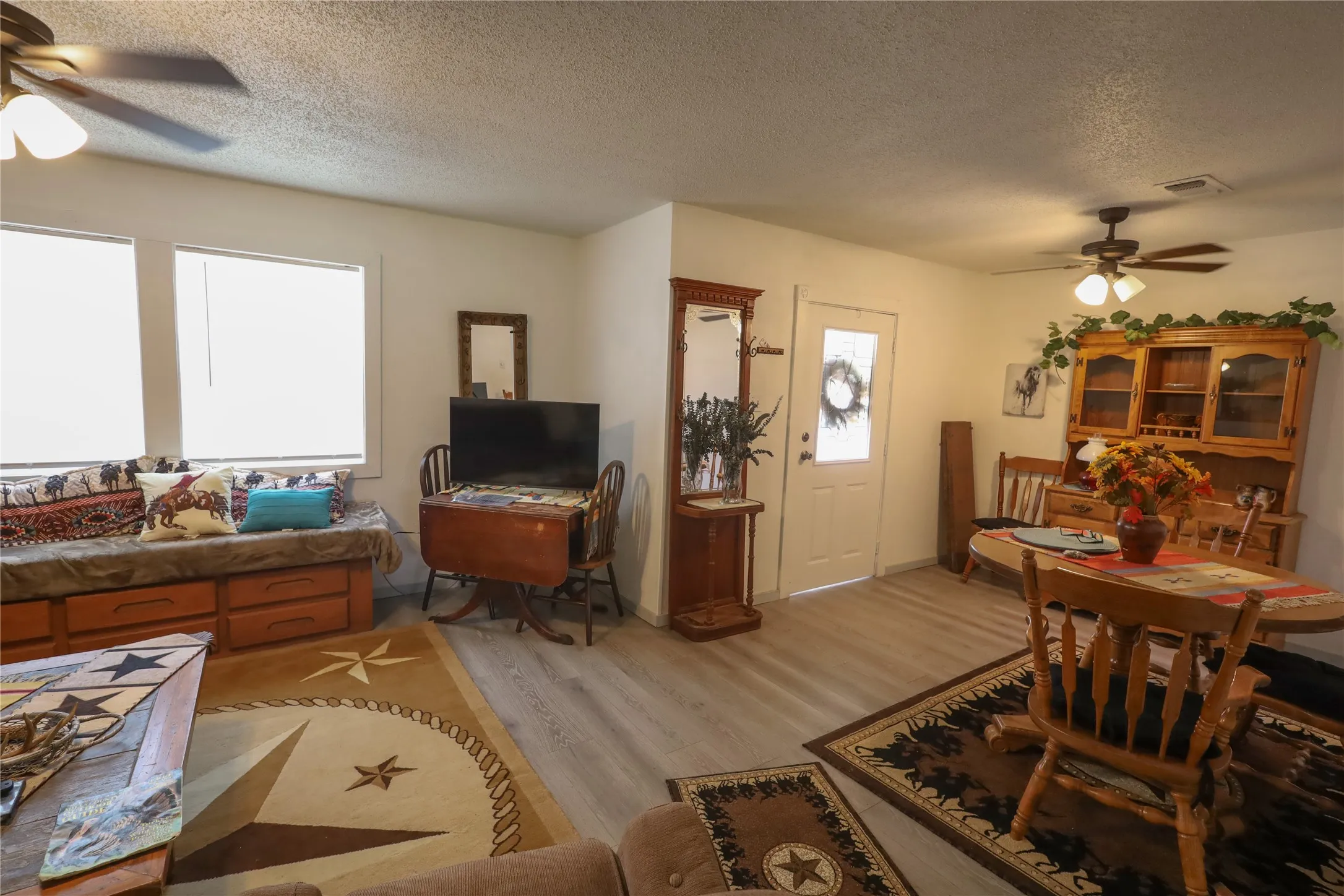 Living room with light hardwood / wood-style flooring, a textured ceiling, and ceiling fan