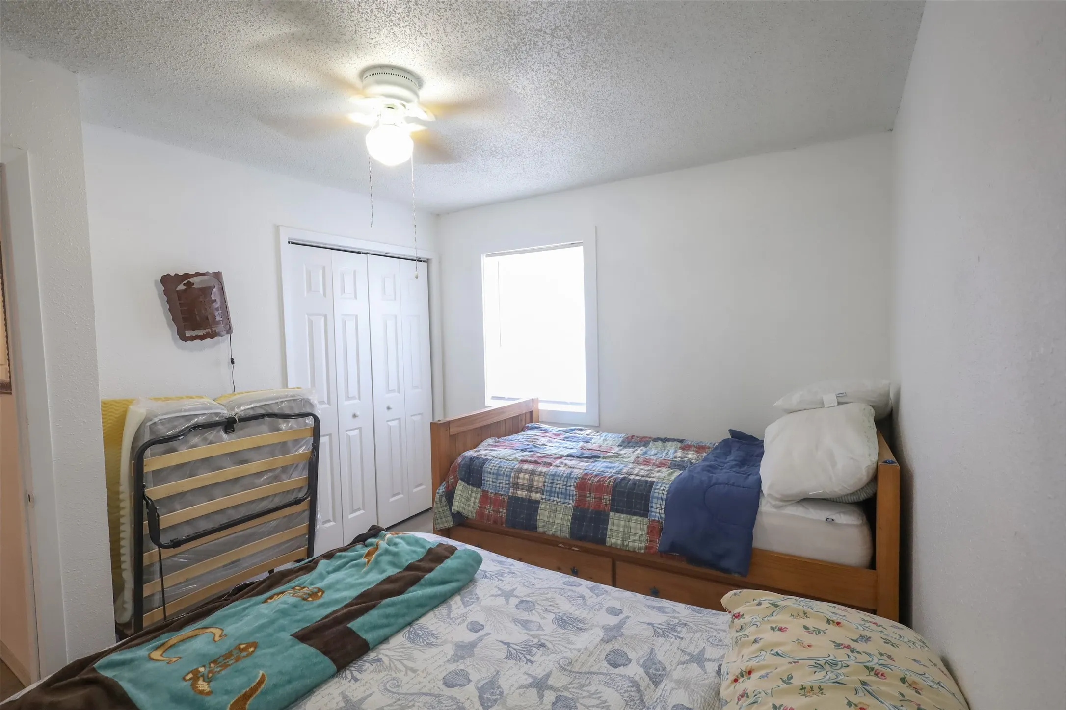 Bedroom with a closet, a textured ceiling, and ceiling fan