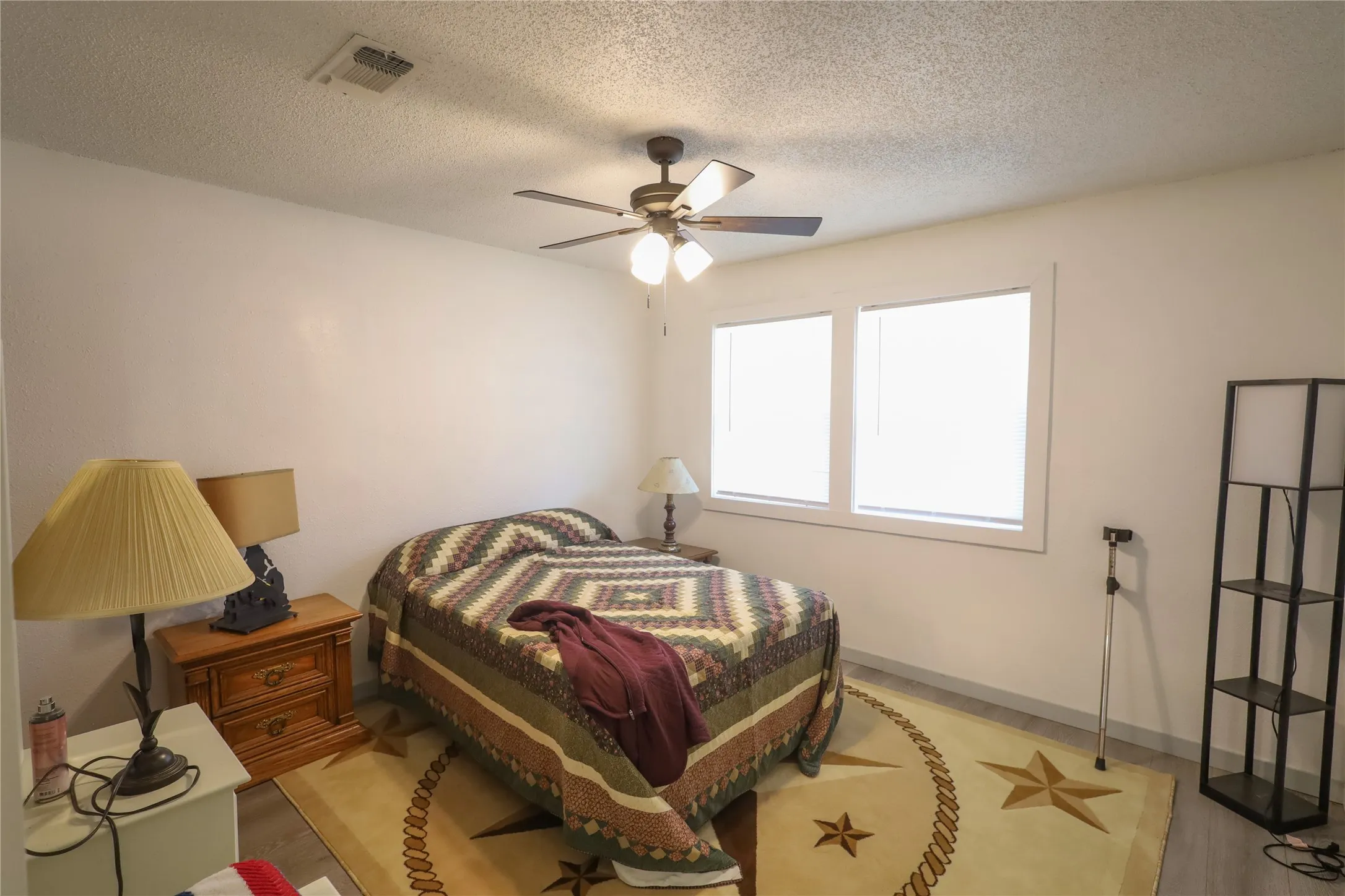 Bedroom with ceiling fan, a textured ceiling, and light hardwood / wood-style flooring