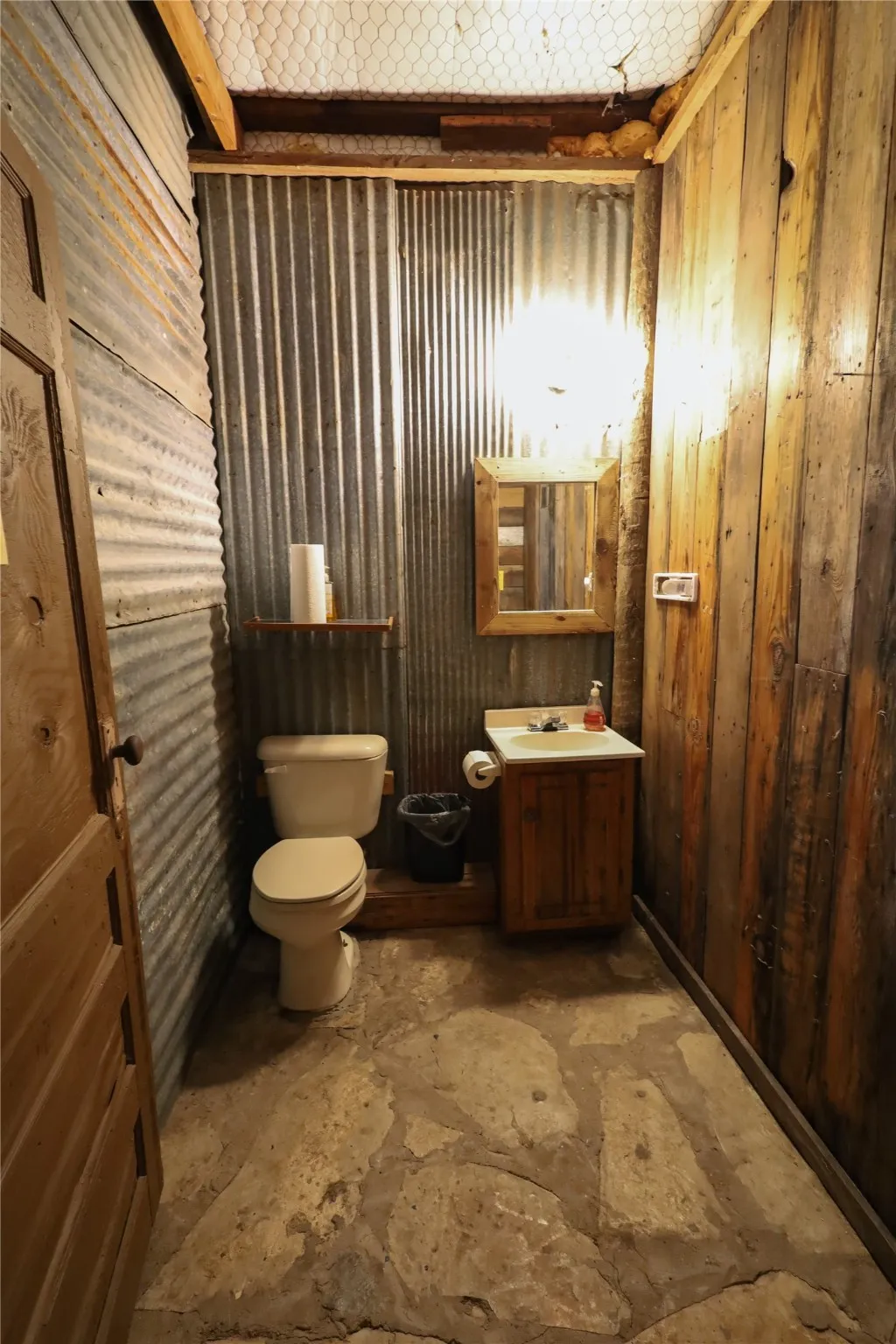 Bathroom featuring vanity, wooden walls, and toilet