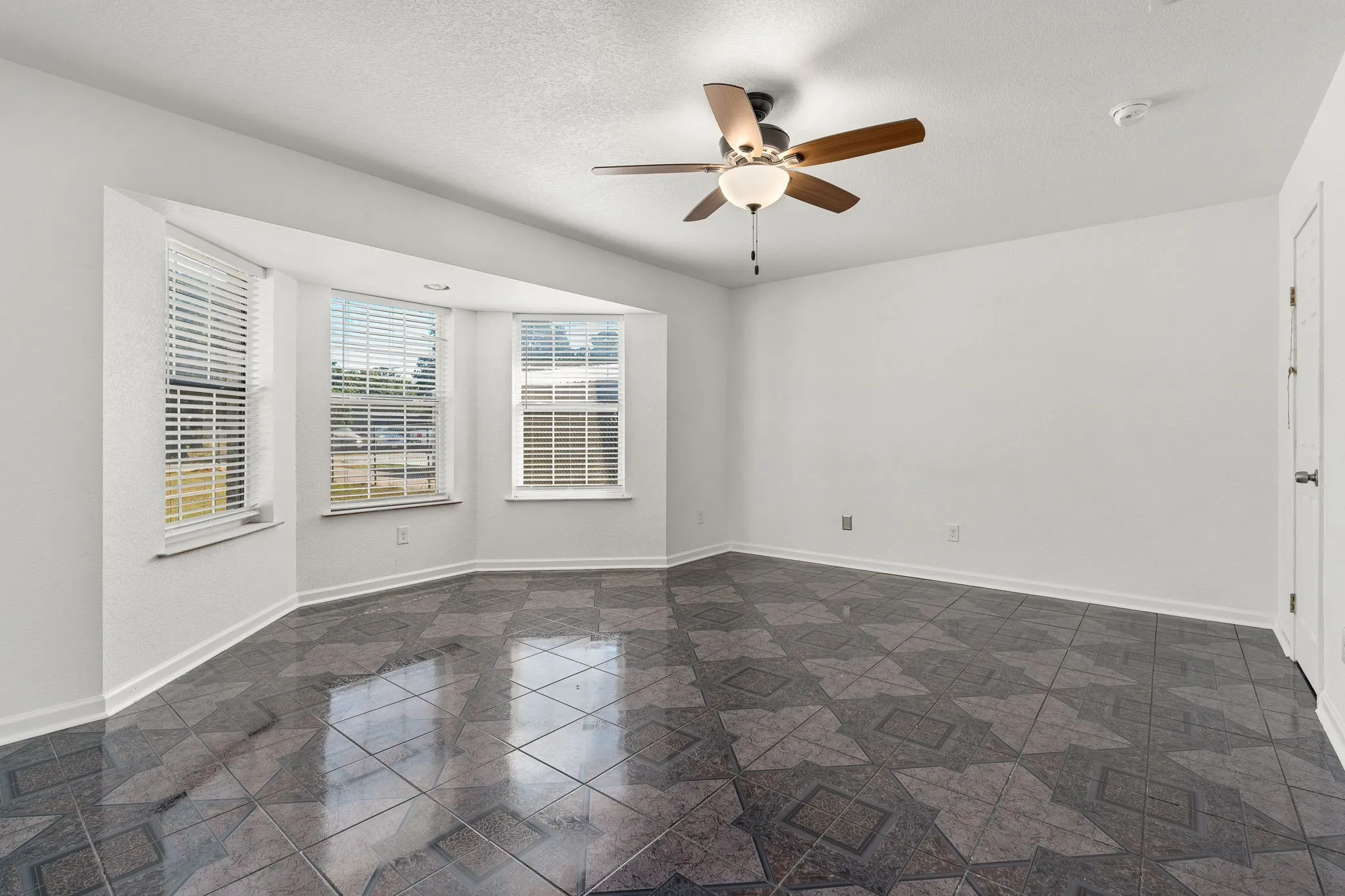 Empty room with ceiling fan and a textured ceiling