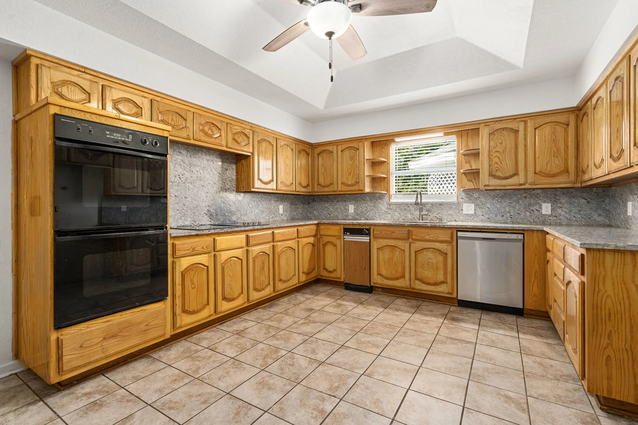 Kitchen with sink, backsplash, black appliances, and a tray ceiling