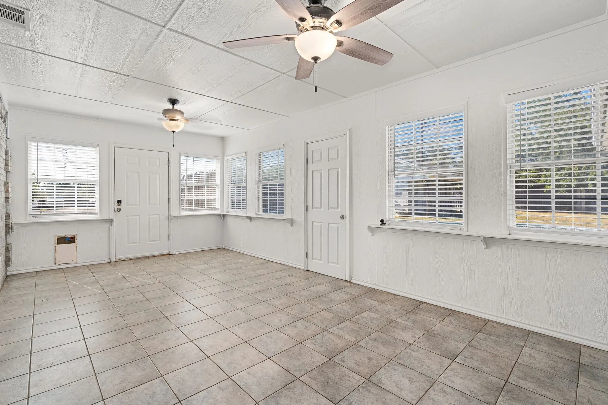 Unfurnished room with ceiling fan, a healthy amount of sunlight, and light tile patterned floors