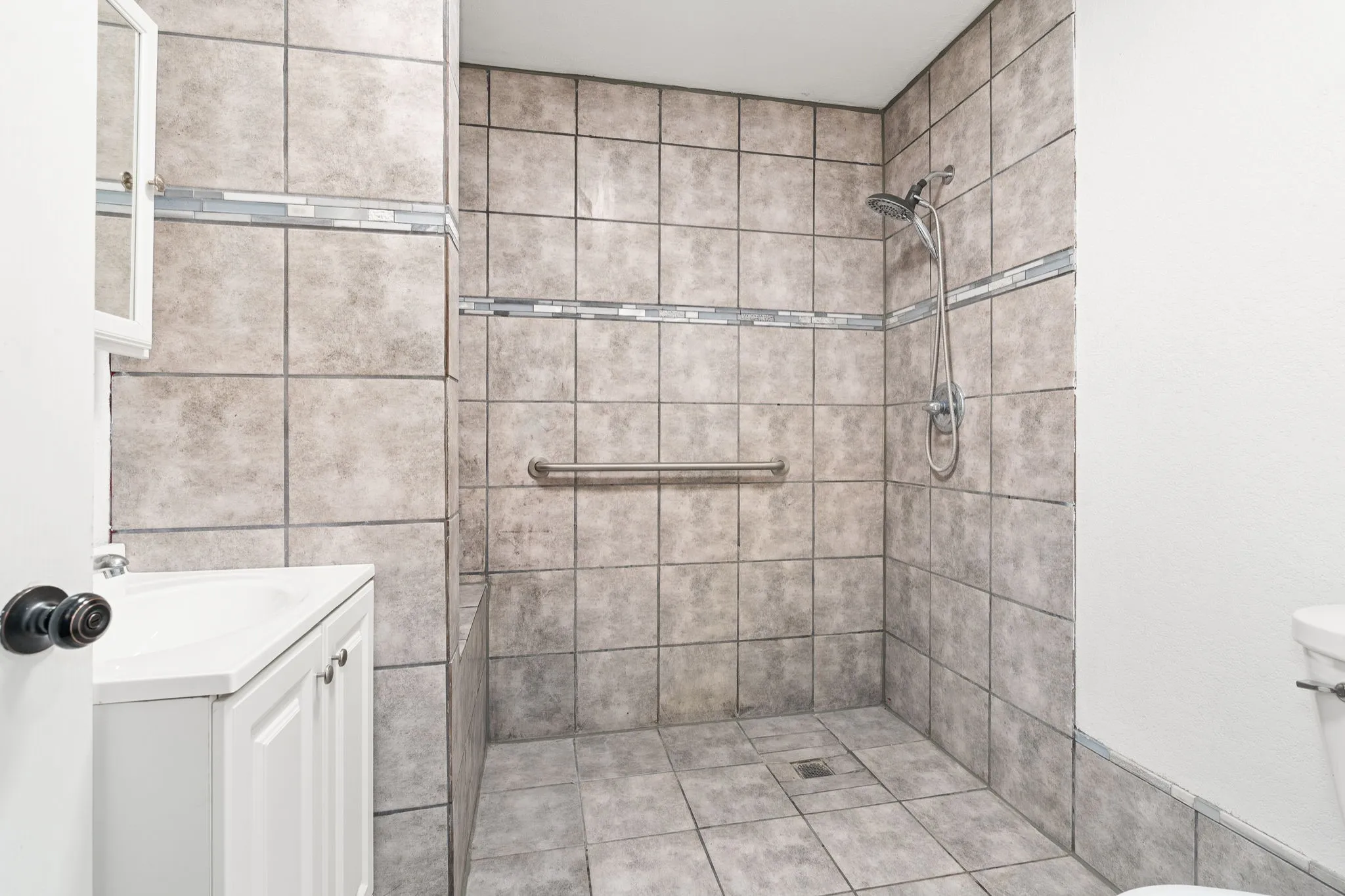 Bathroom with vanity, toilet, tile patterned floors, and tiled shower