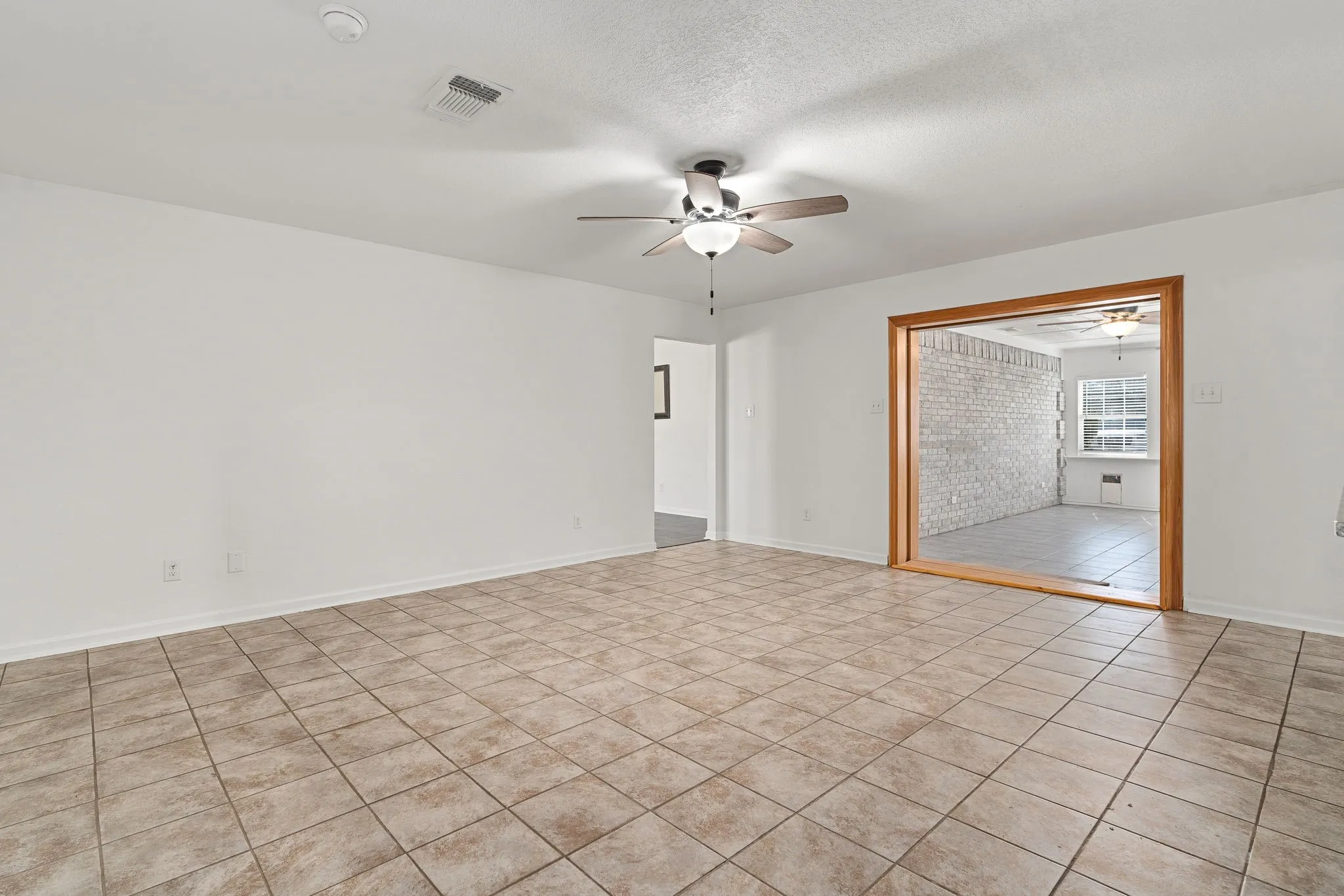 Empty room featuring a textured ceiling, light tile patterned floors, and ceiling fan