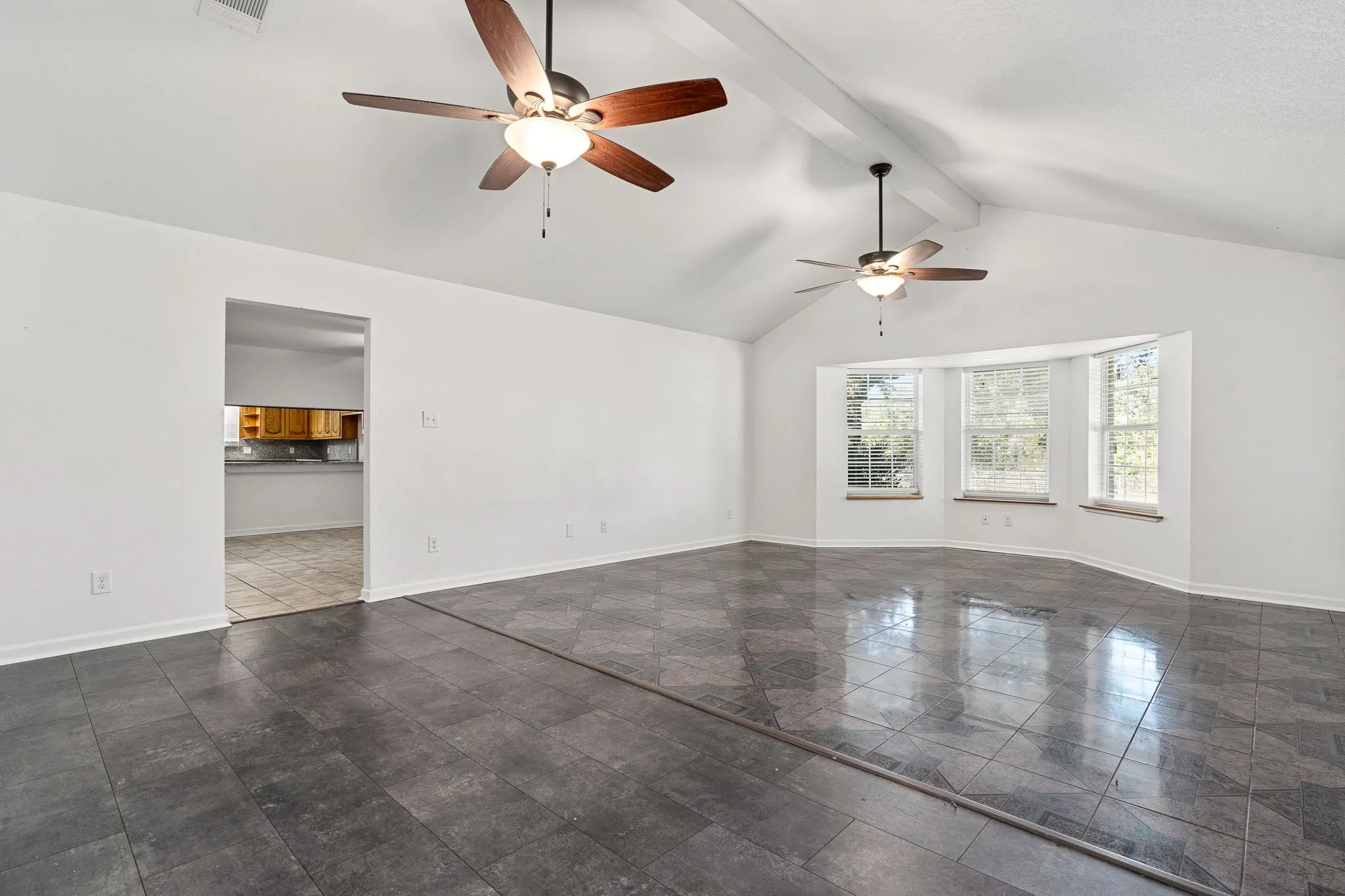 Spare room featuring ceiling fan, high vaulted ceiling, and beamed ceiling