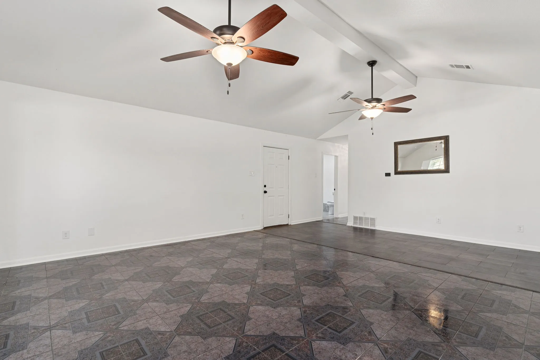 Empty room with lofted ceiling with beams and ceiling fan