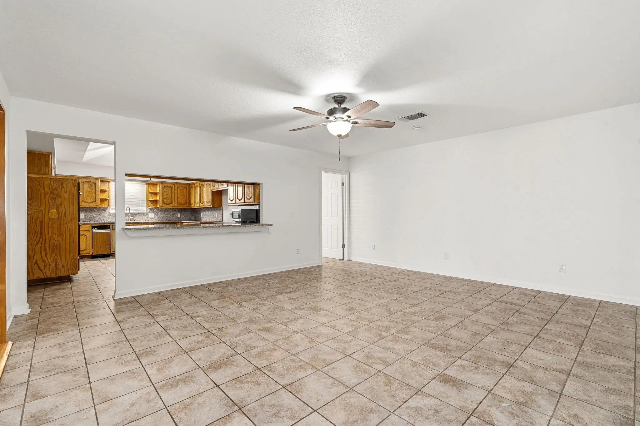 Unfurnished living room with light tile patterned floors and ceiling fan