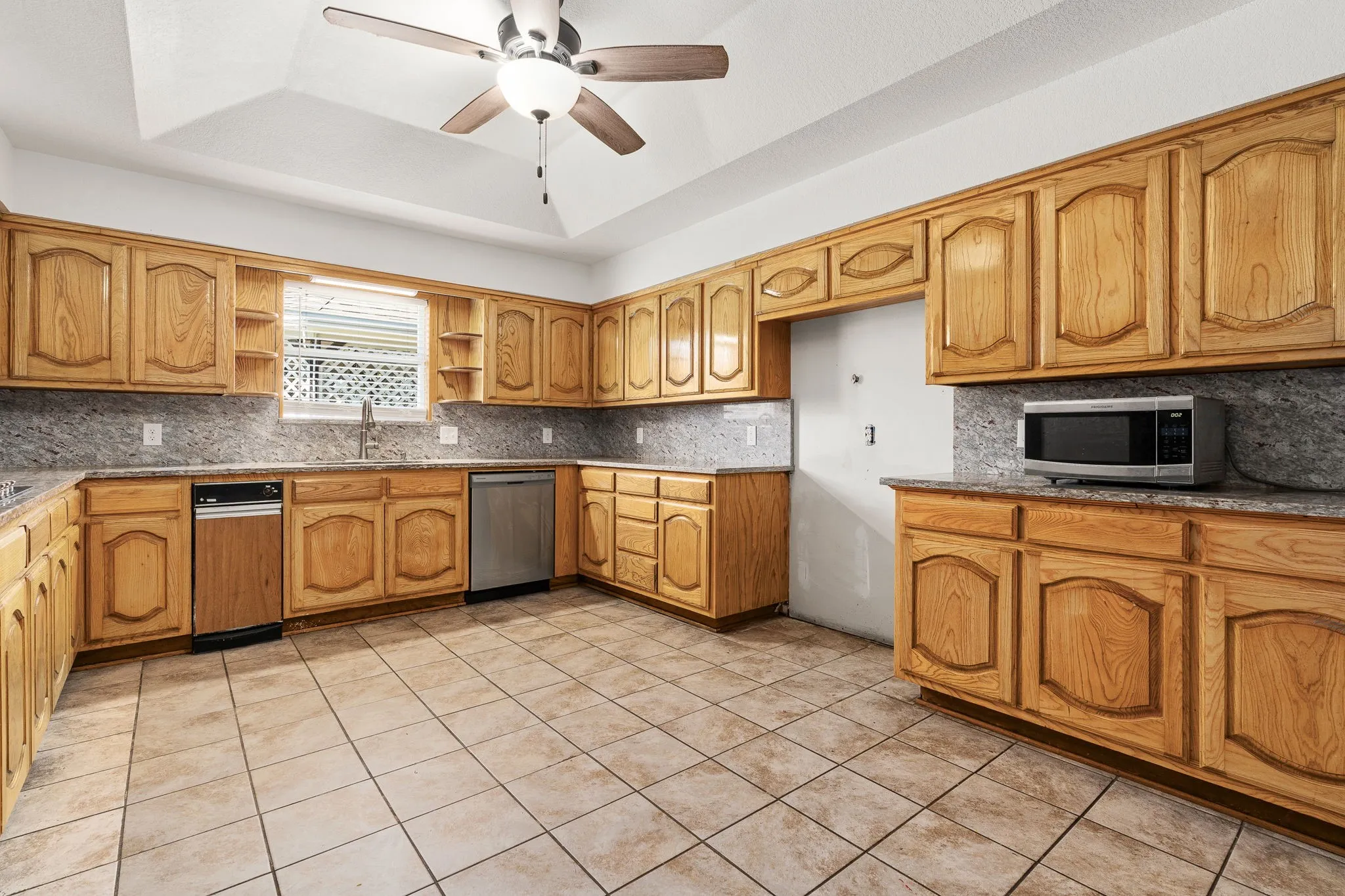 Kitchen with tasteful backsplash, sink, light tile patterned flooring, a raised ceiling, and stainless steel appliances