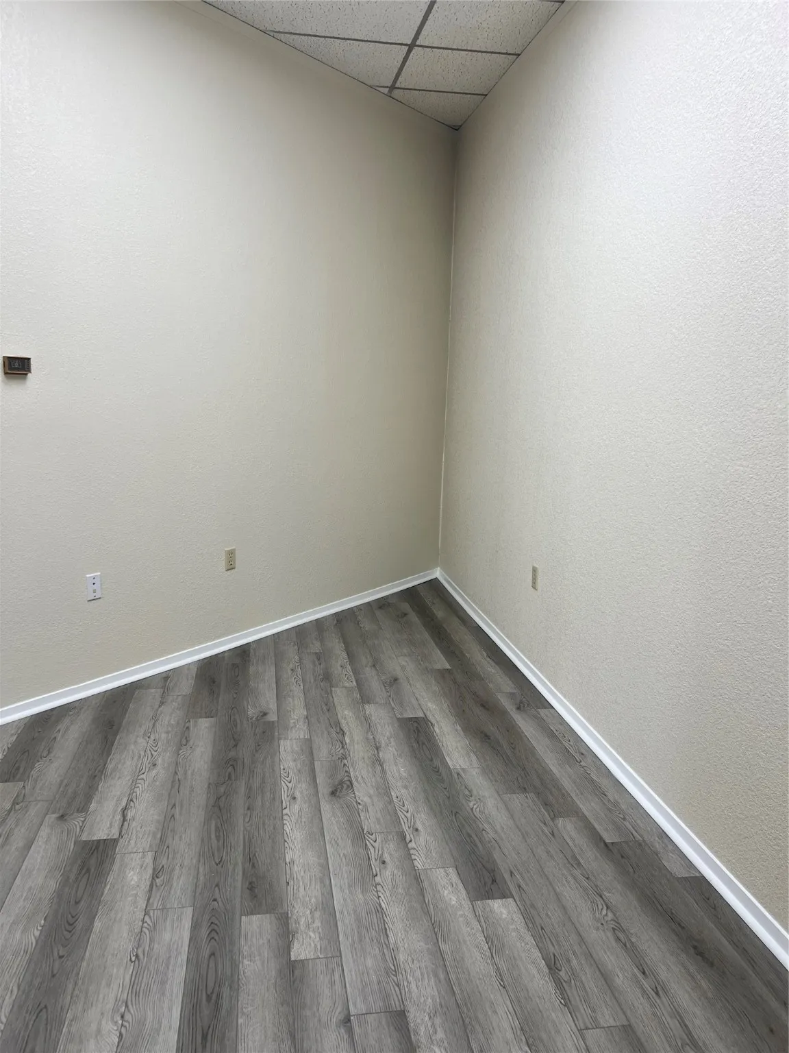 Unfurnished room featuring a paneled ceiling and dark hardwood / wood-style floors