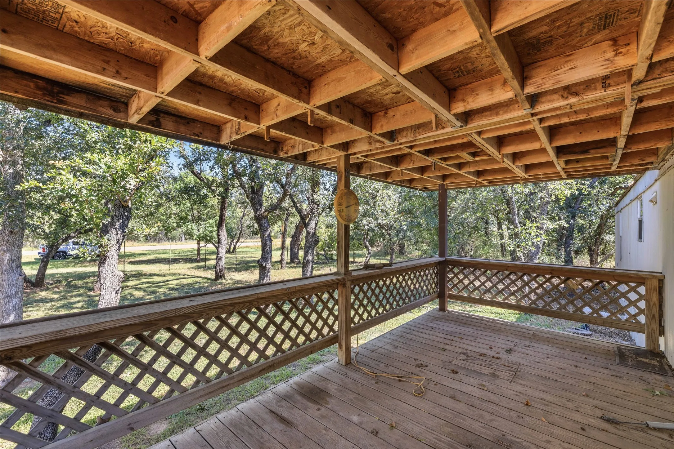 Covered outdoor deck with wood flooring and lattice railing