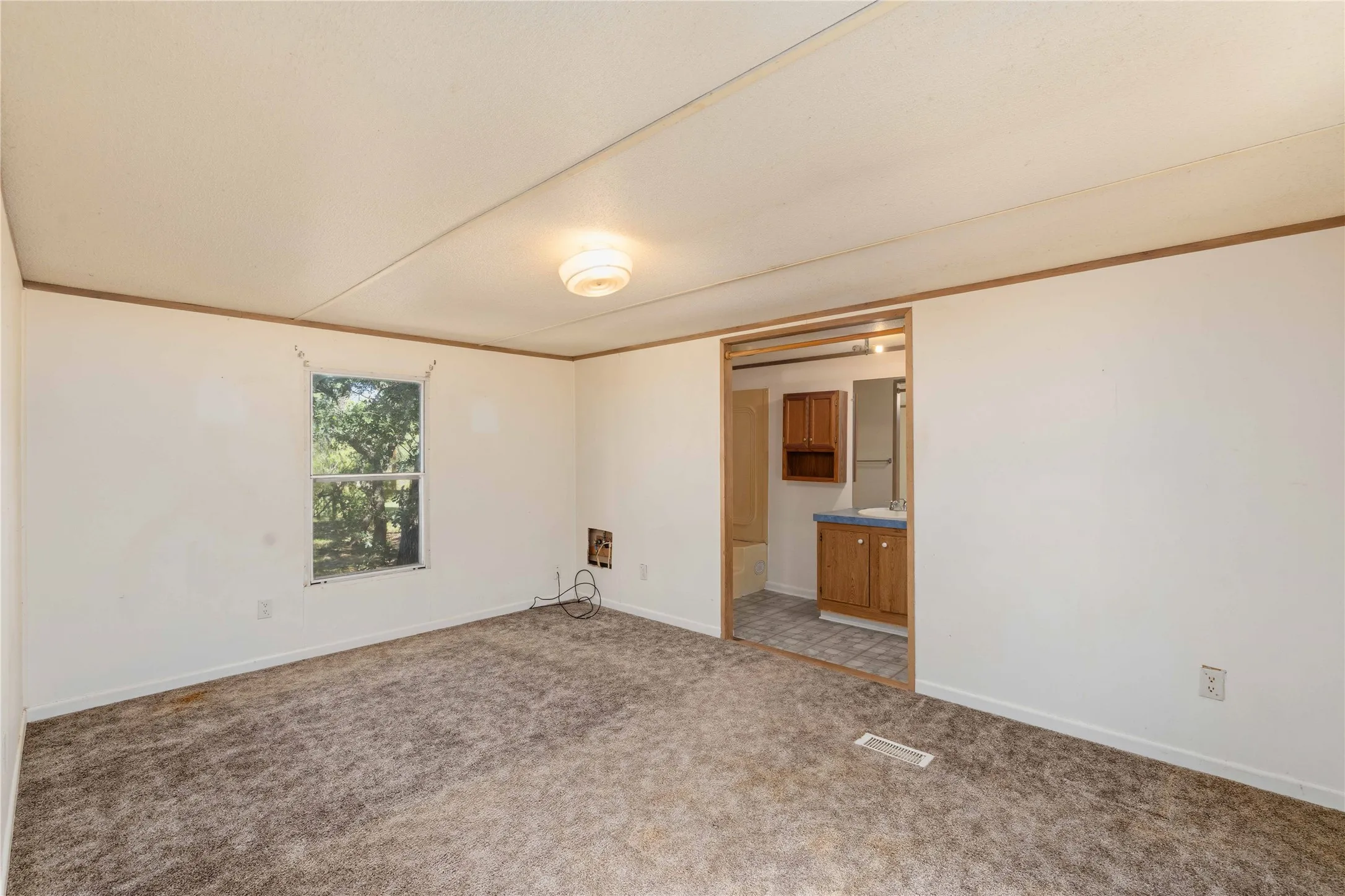 Carpeted room with white walls and a single window offering natural light