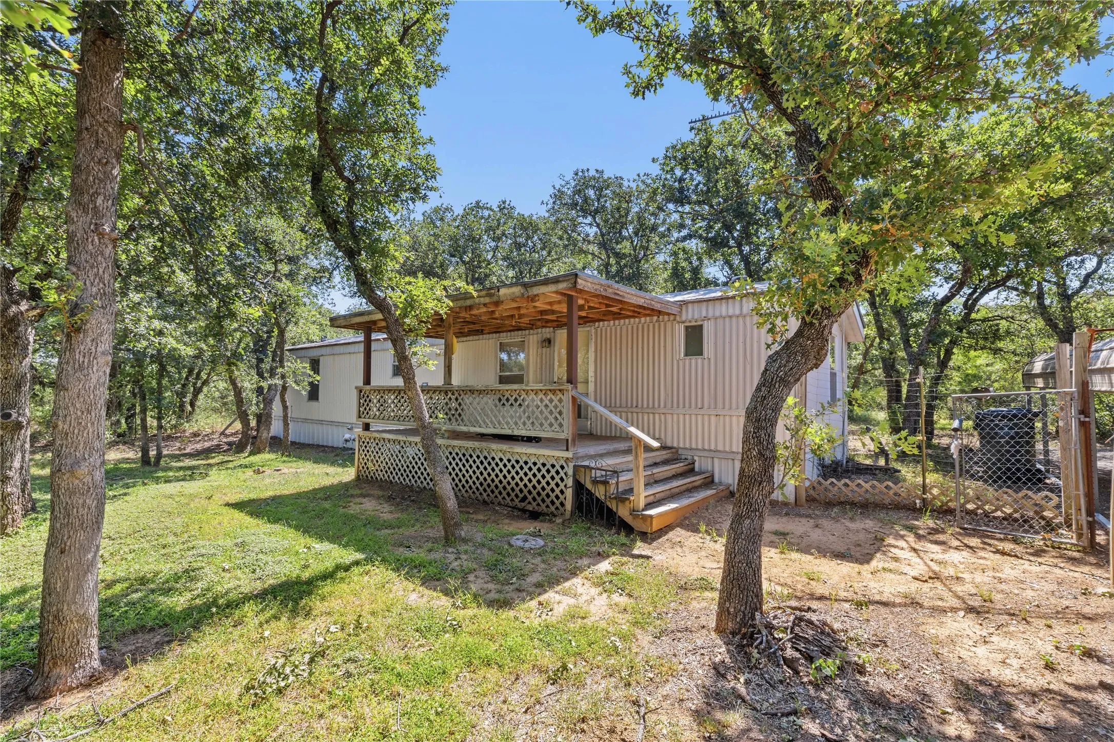 Exterior property featuring vertical siding, a covered deck with lattice skirting, and natural wood steps