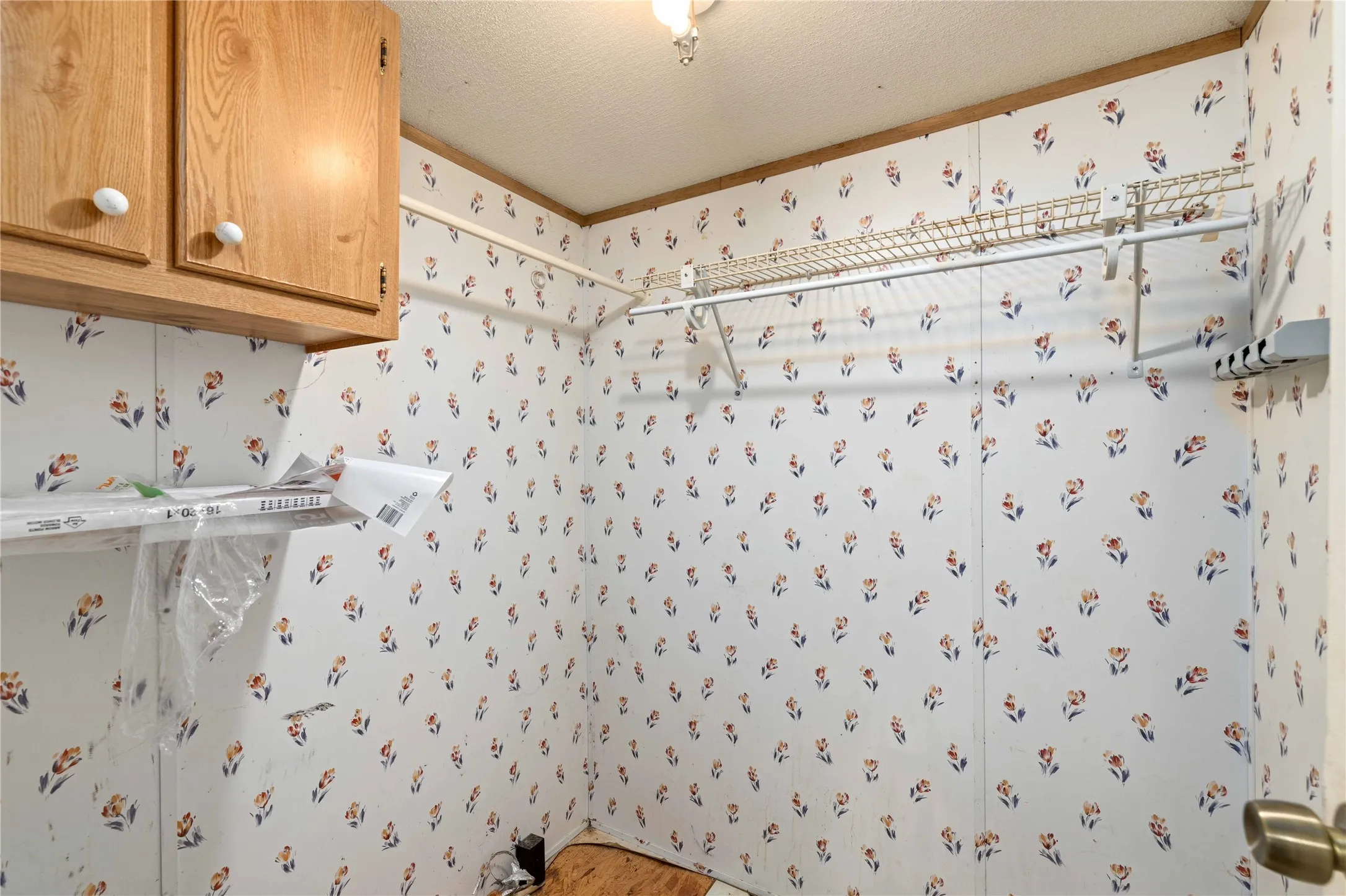 Utility space featuring wood-finish cabinetry, wire shelving, and a wall-mounted clothing rod