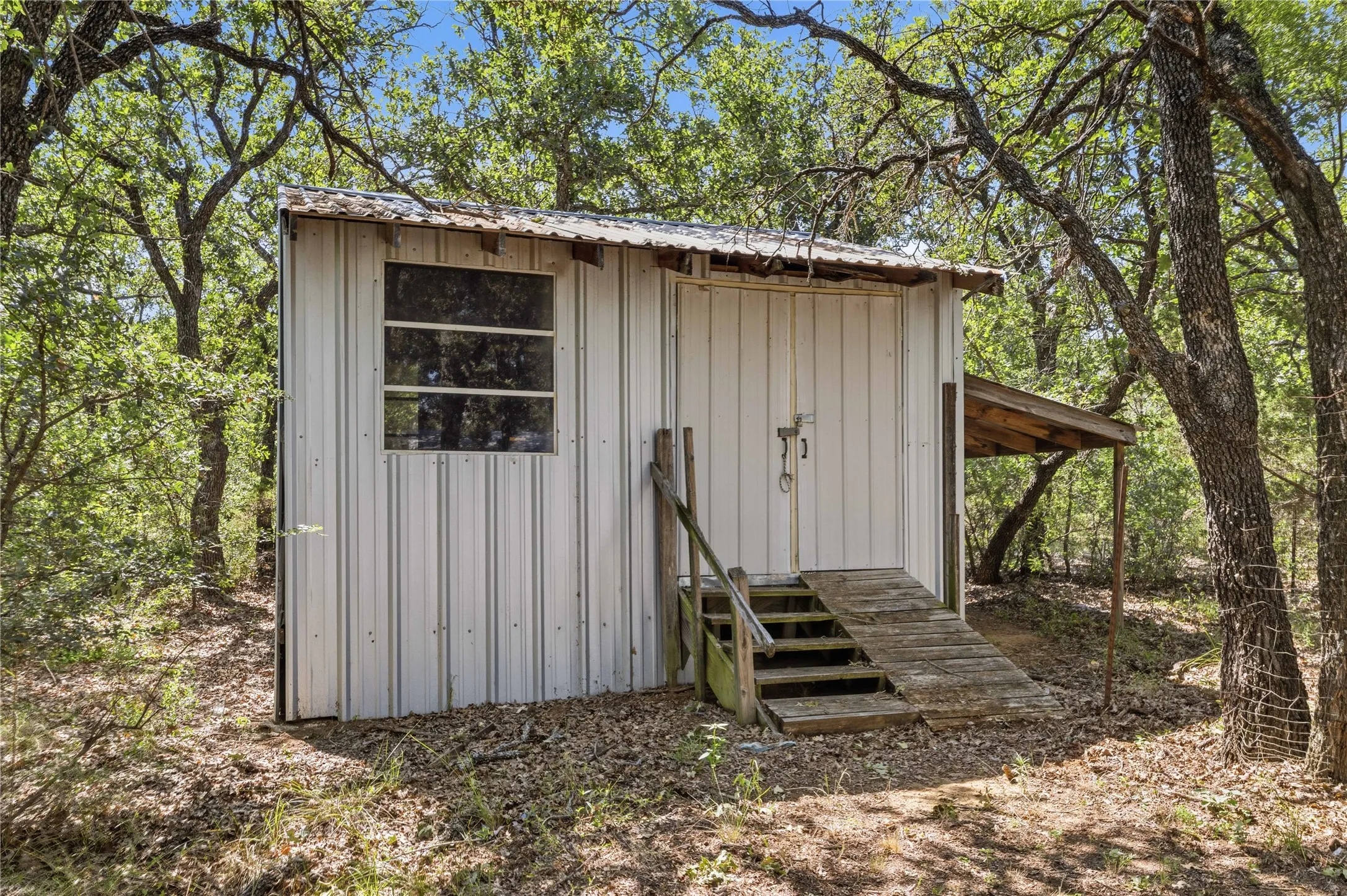 Corrugated metal structure featuring a multi-pane window and a covered side porch