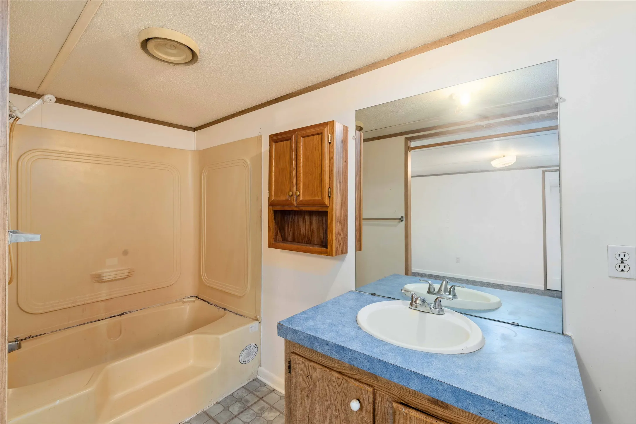 Bathroom featuring a single vanity with an oval sink, a blue countertop, and a built-in mirror