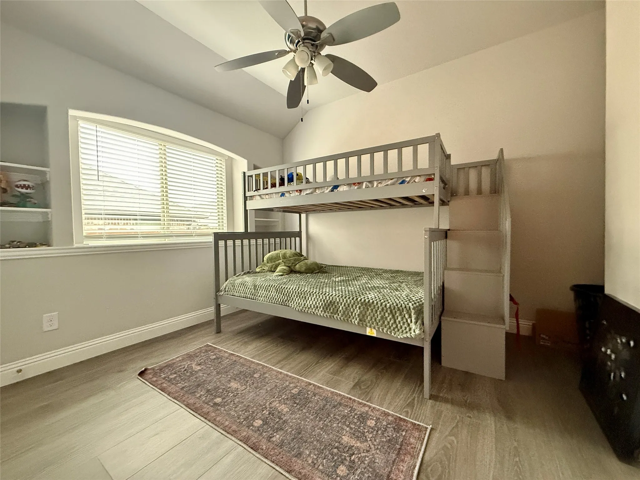 Bedroom with wood- laminate style floors, ceiling fan, and high ceiling