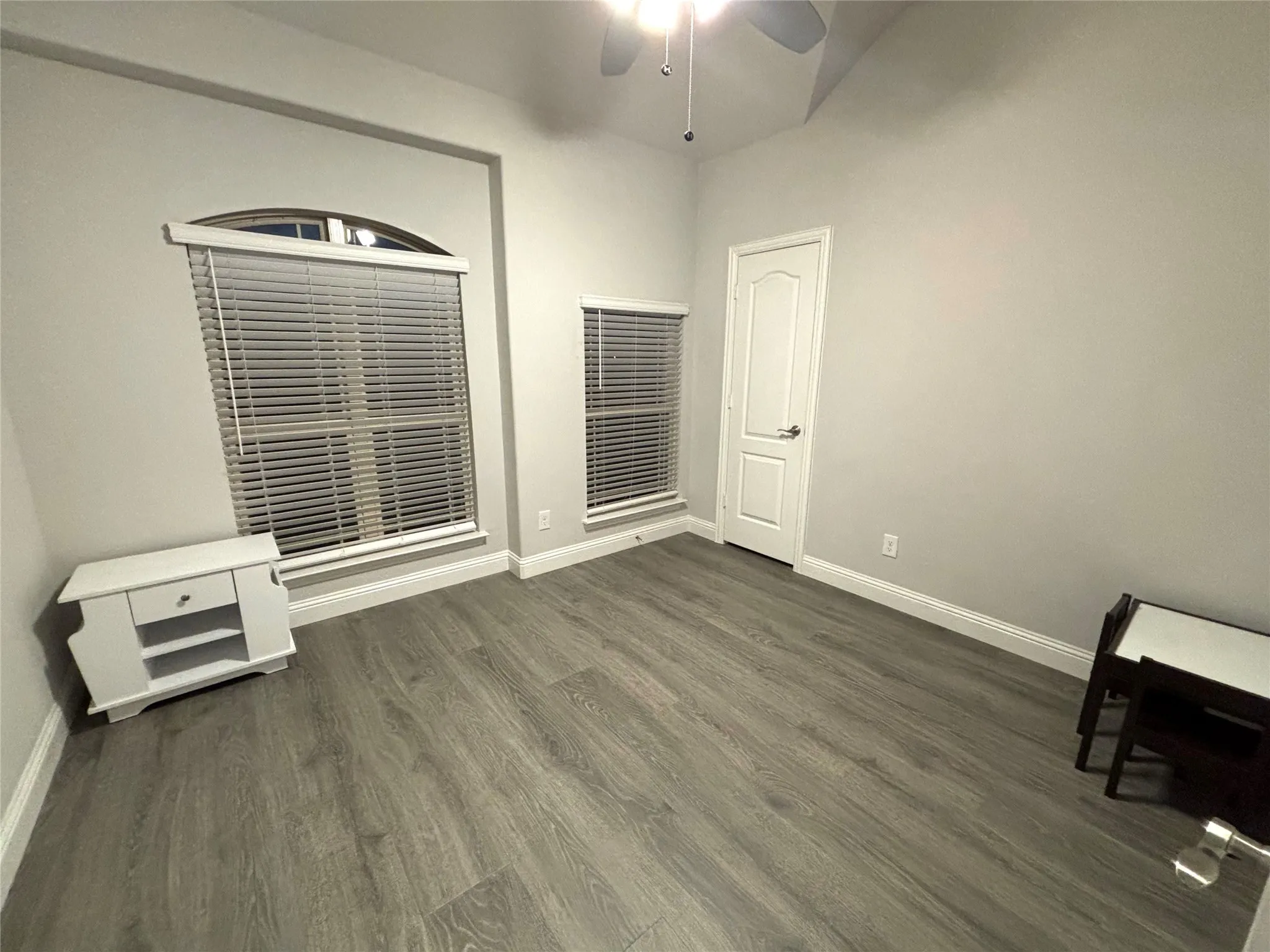 Empty room with ceiling fan and dark wood-type flooring