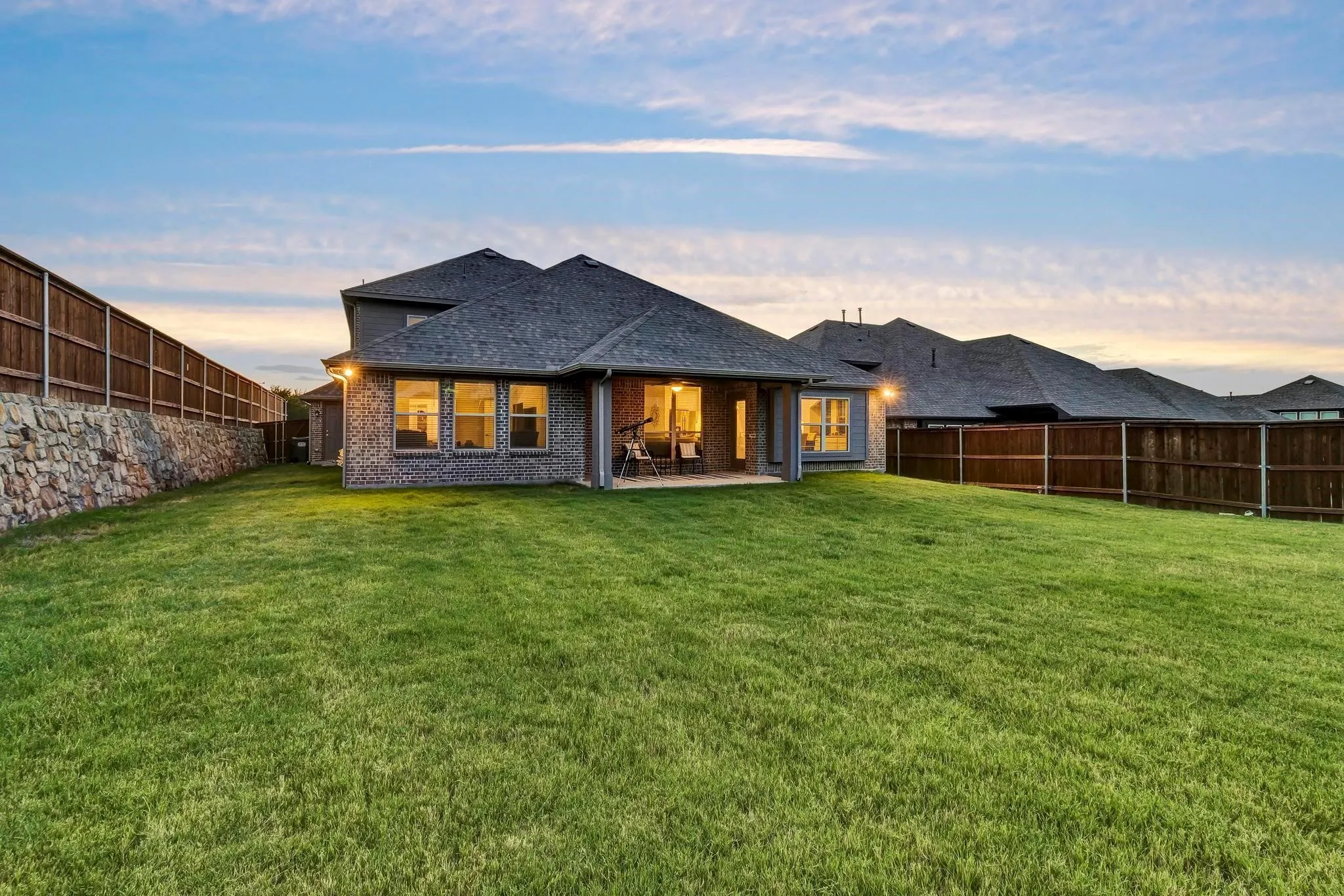 Back house at dusk with a patio area and a lawn
