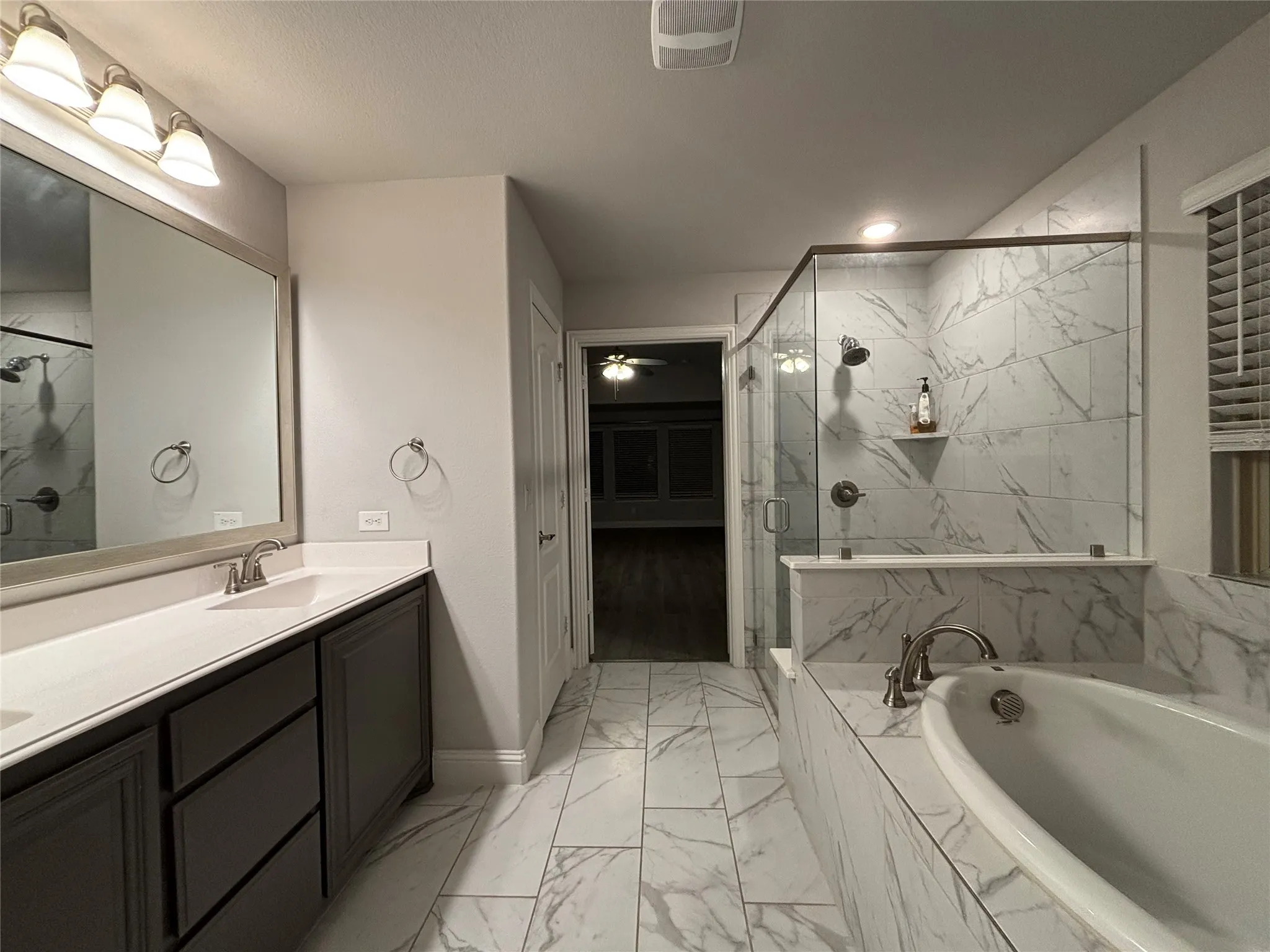 Bathroom featuring shower with separate bathtub and vanity
