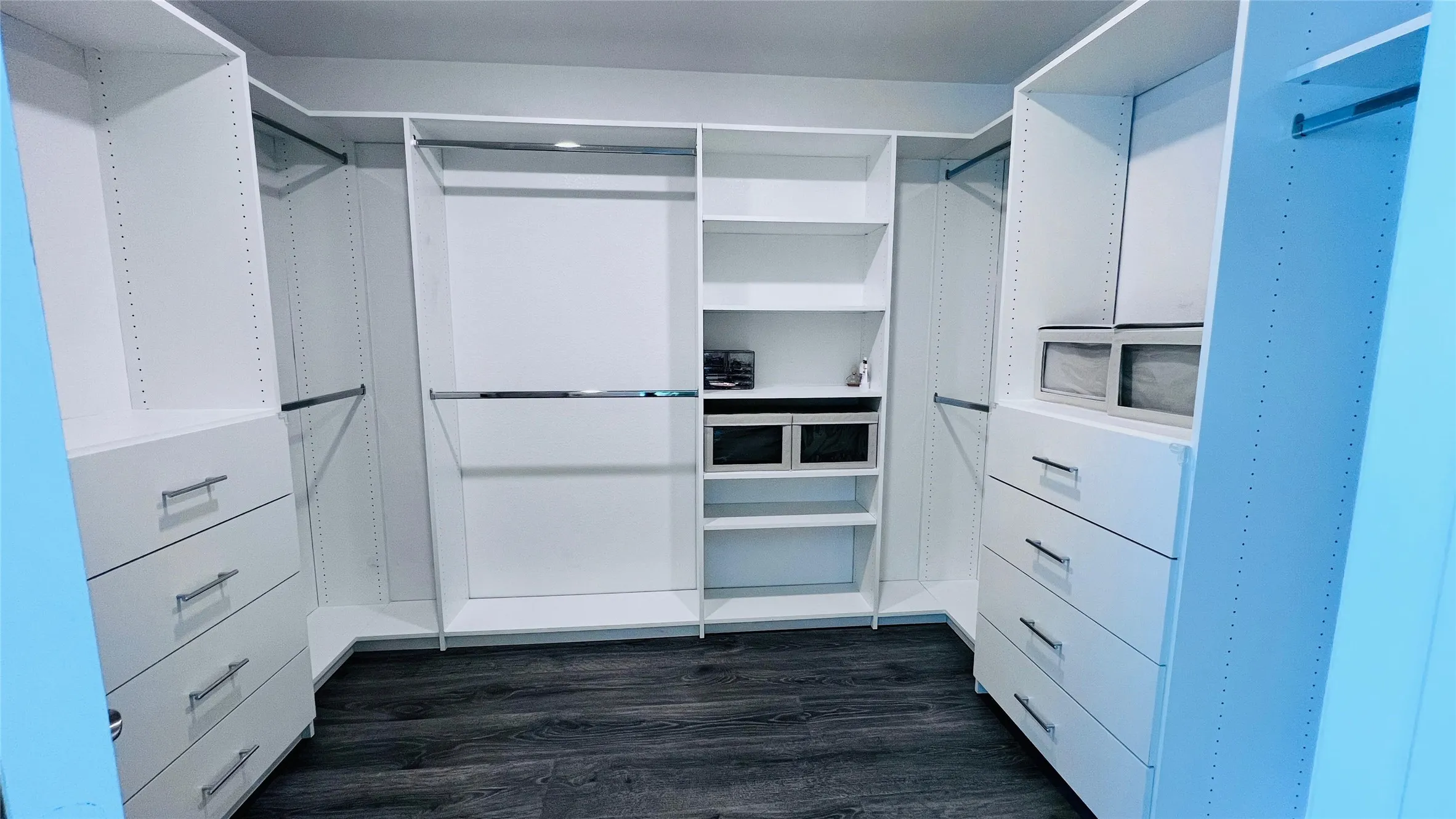 Walk in closet with dark hardwood / wood-style flooring