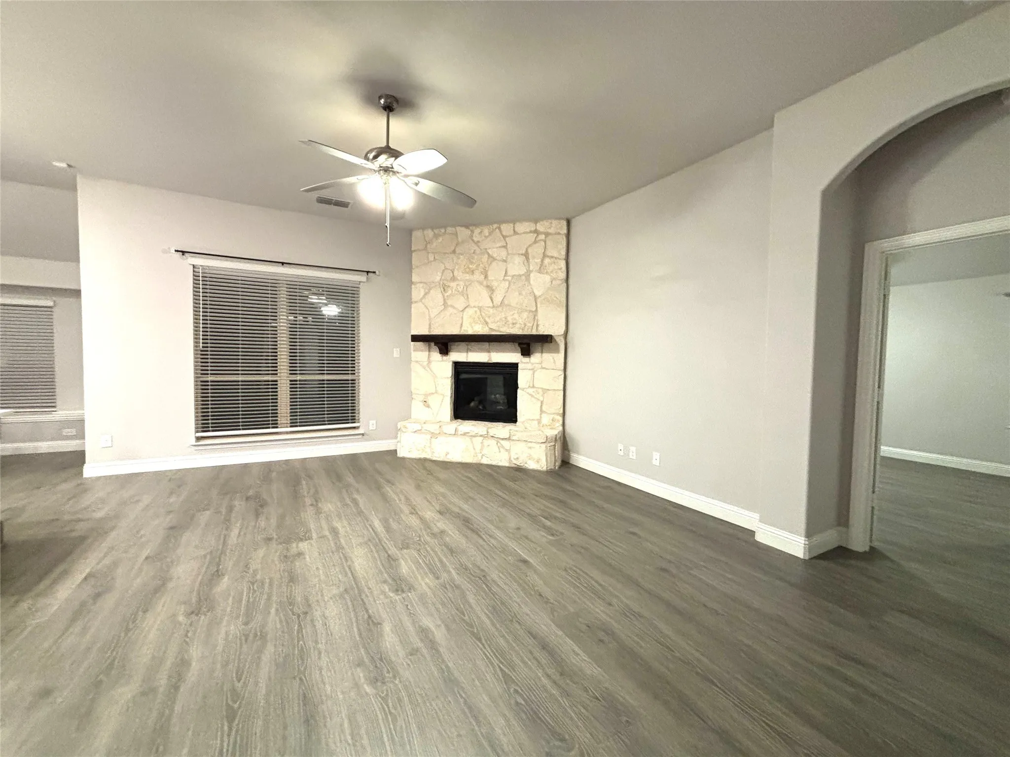 Unfurnished living room with a fireplace, ceiling fan, and dark wood-type flooring