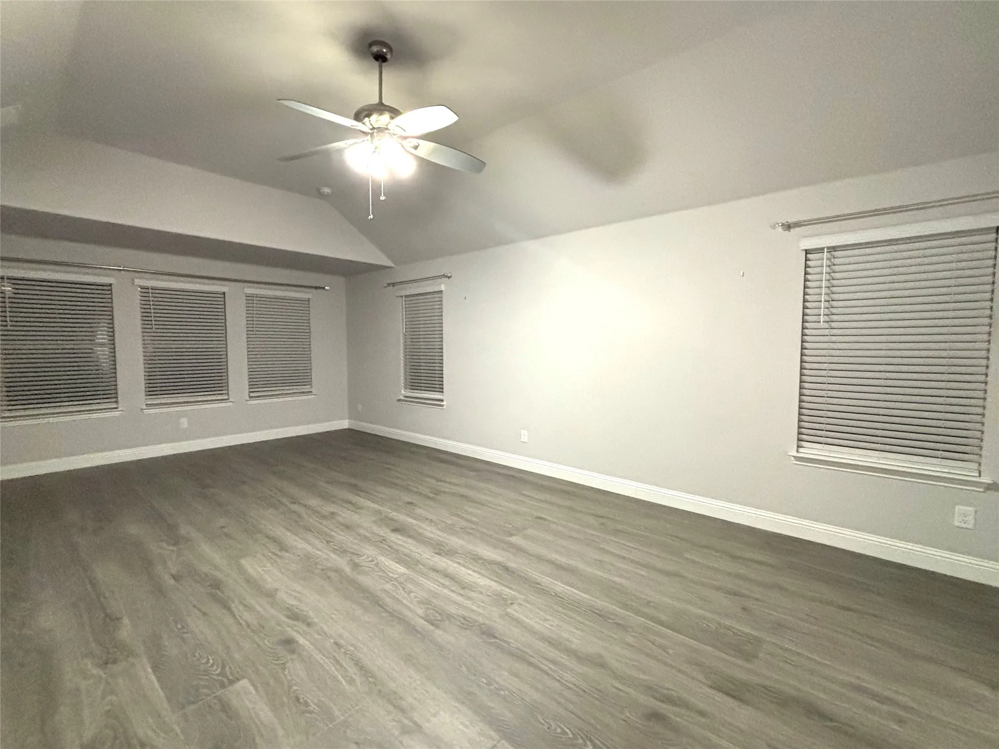 Spare room with ceiling fan, dark wood-type flooring, and lofted ceiling