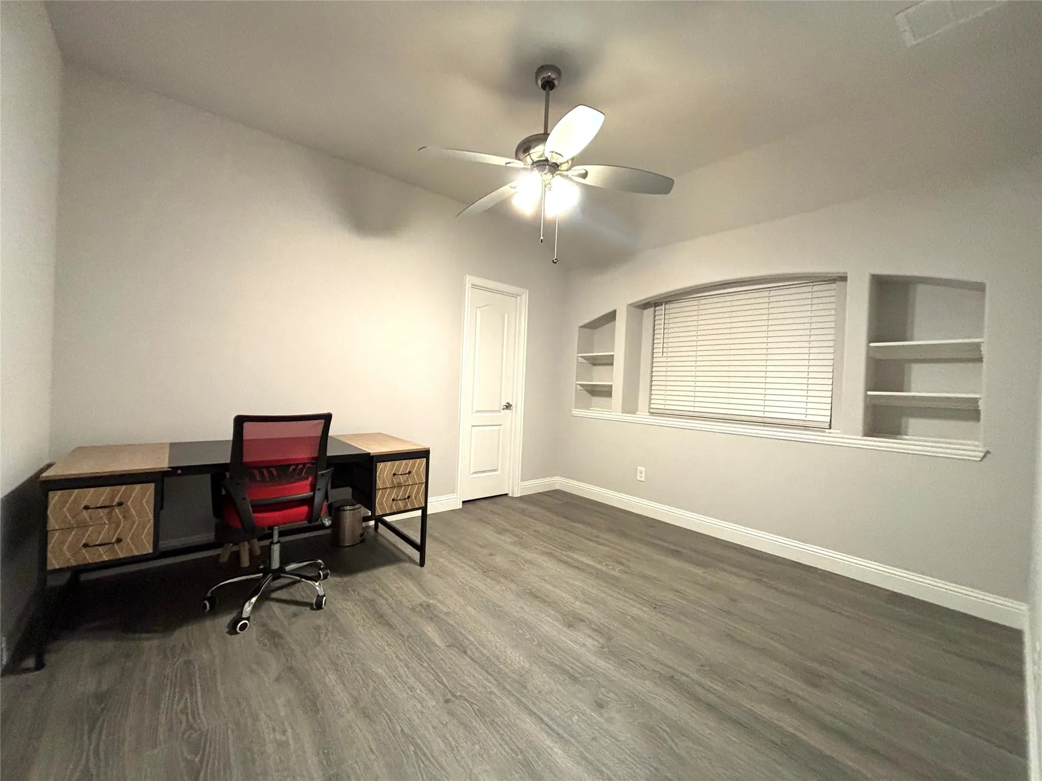 Home office with ceiling fan, built in features, and dark wood-type flooring