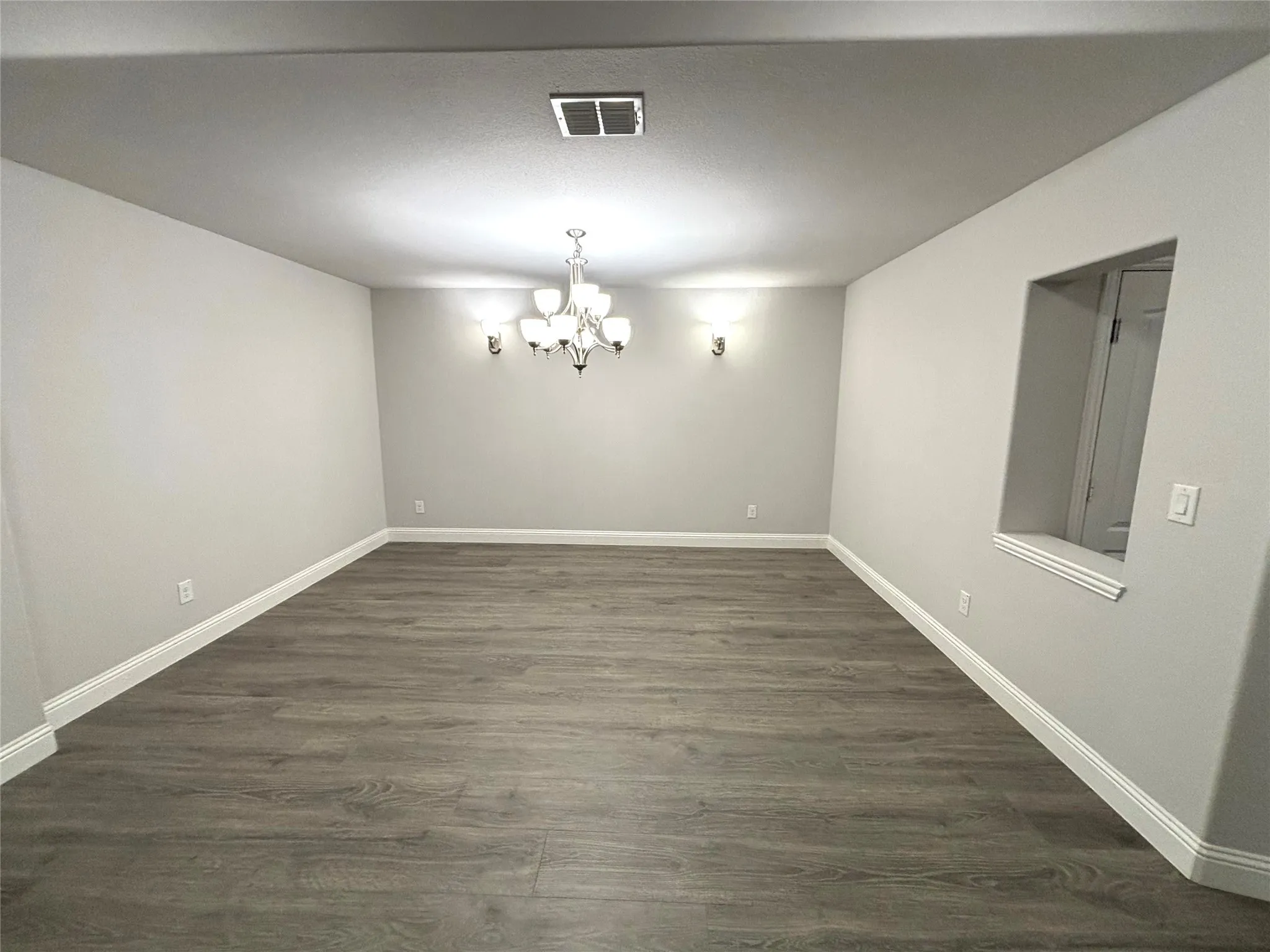 Unfurnished dining area featuring dark hardwood / wood-style floors and a notable chandelier