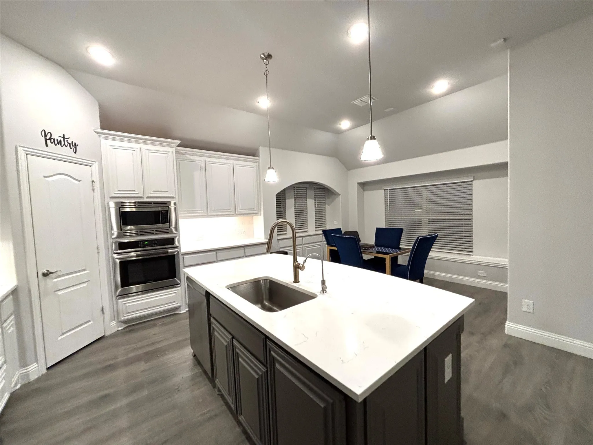 Kitchen featuring white cabinetry, sink, pendant lighting, vaulted ceiling, and appliances with stainless steel finishes