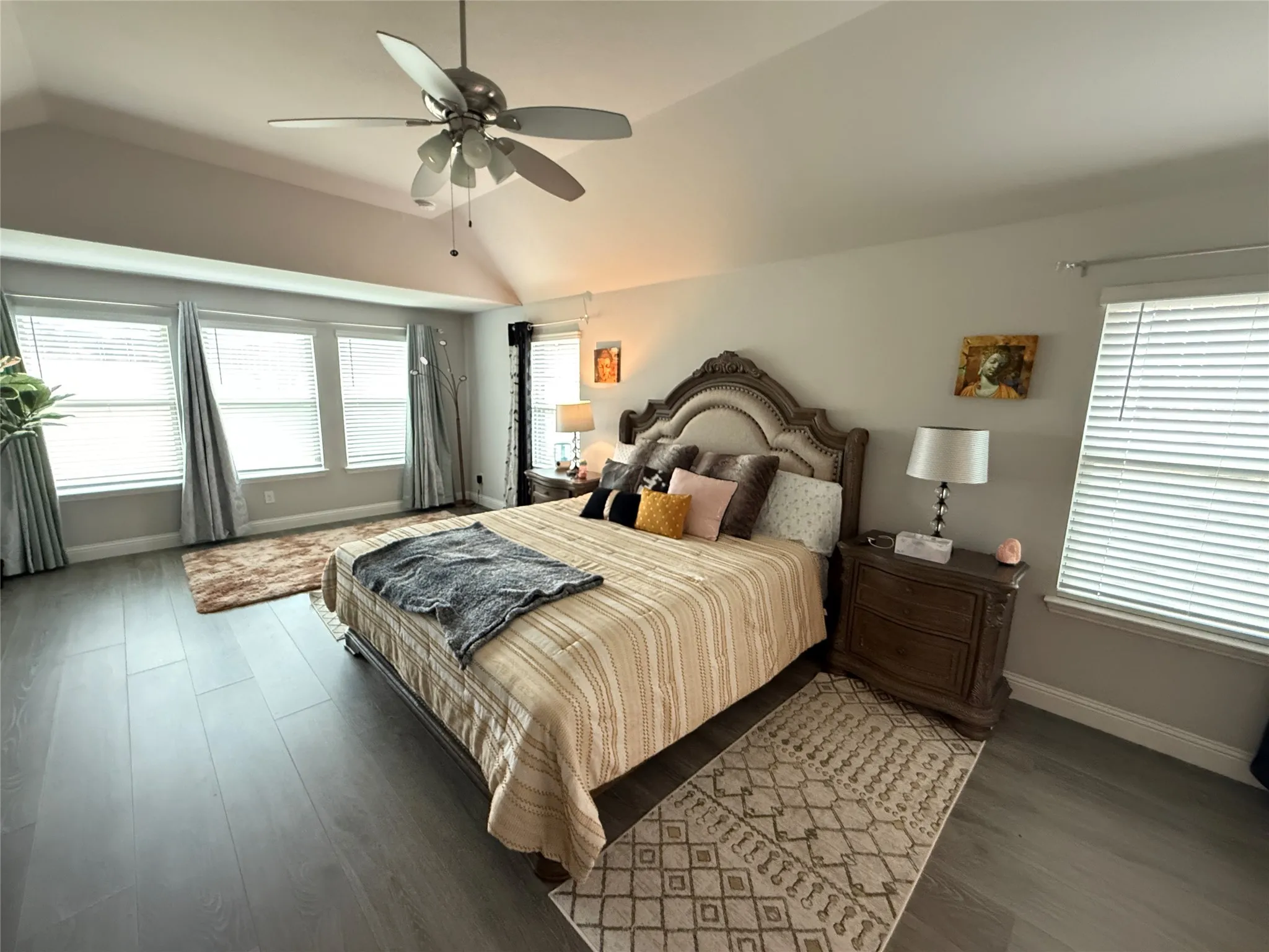 Primary Bedroom featuring high ceiling, multiple windows, and  wood- laminate style flooring