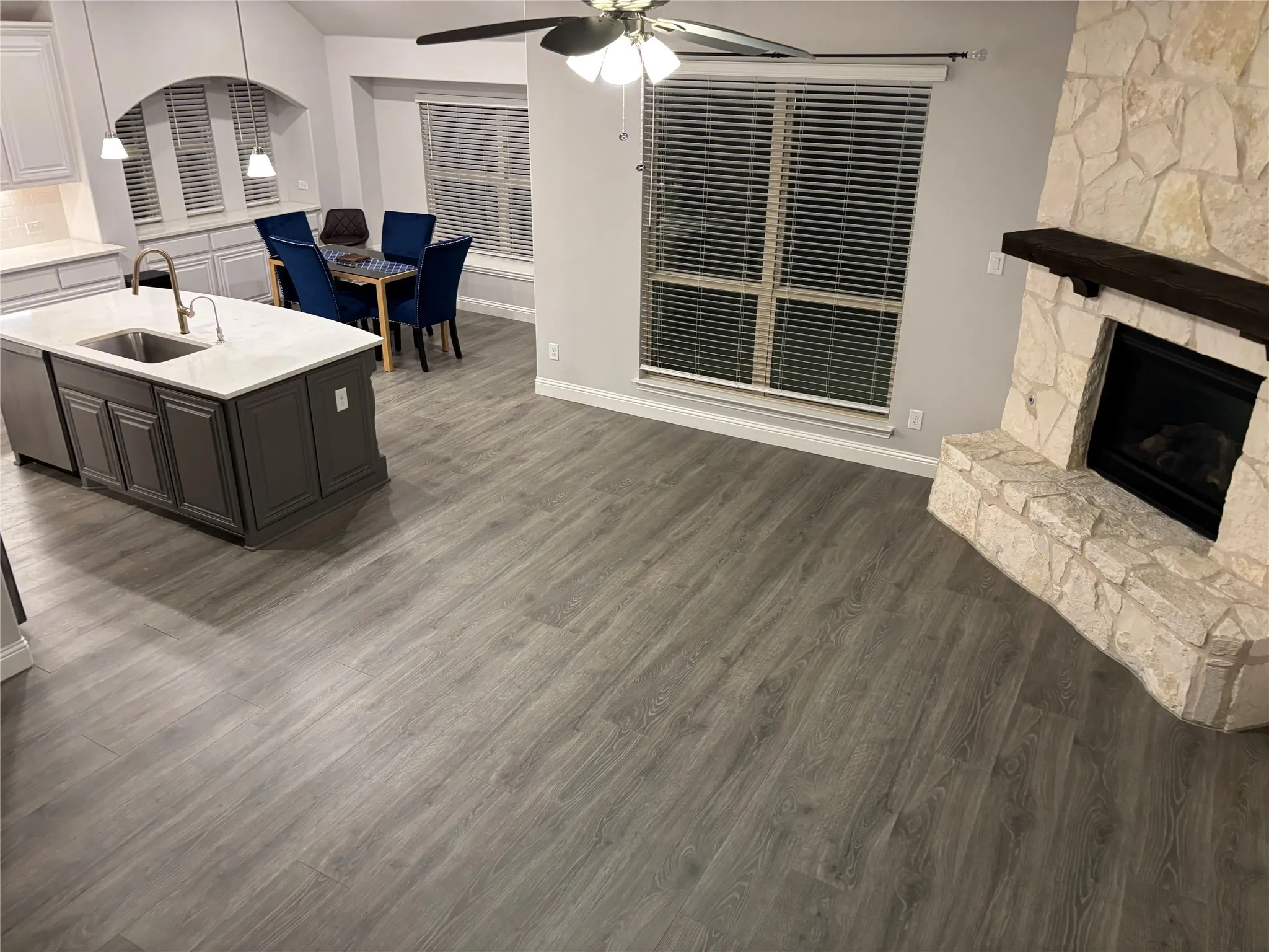 Kitchen featuring a stone fireplace, white cabinetry, sink, and dark wood-type flooring