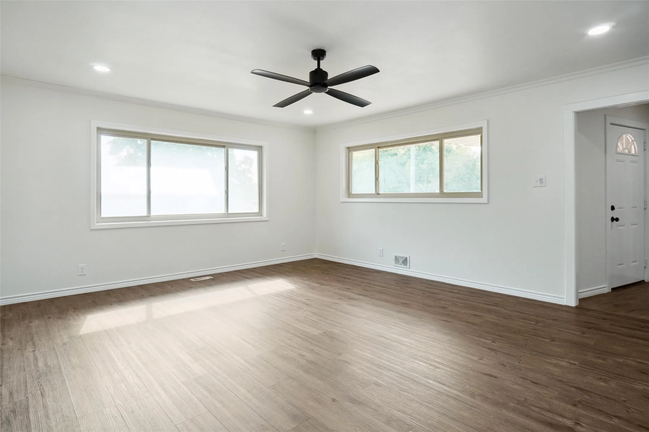 Empty room featuring ornamental molding, dark hardwood / wood-style flooring, a healthy amount of sunlight, and ceiling fan