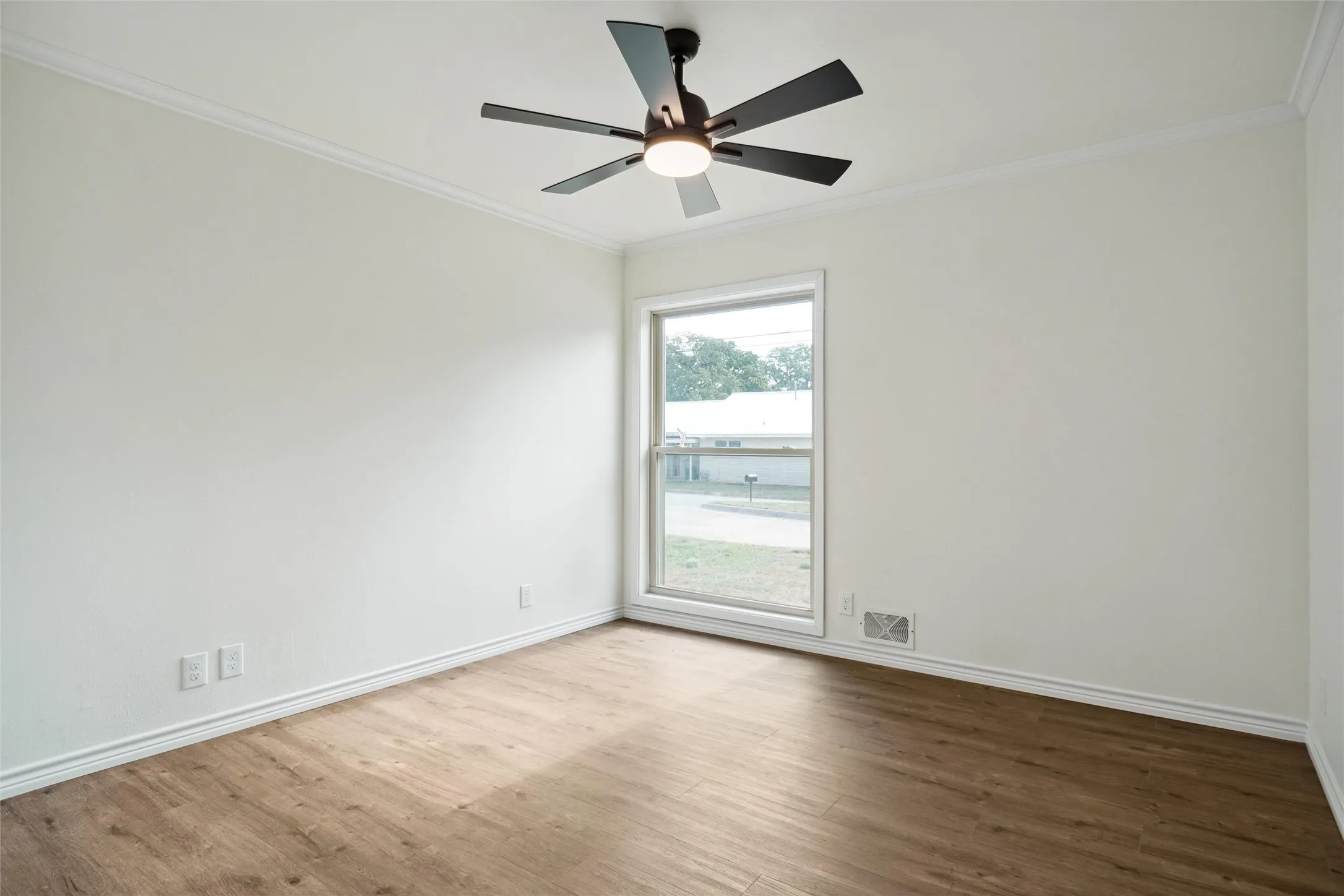 Empty room featuring hardwood / wood-style floors, ceiling fan, and crown molding