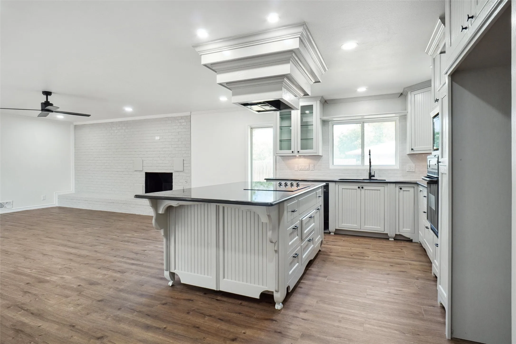 Kitchen featuring dark hardwood / wood-style flooring, white cabinets, a breakfast bar, and a center island