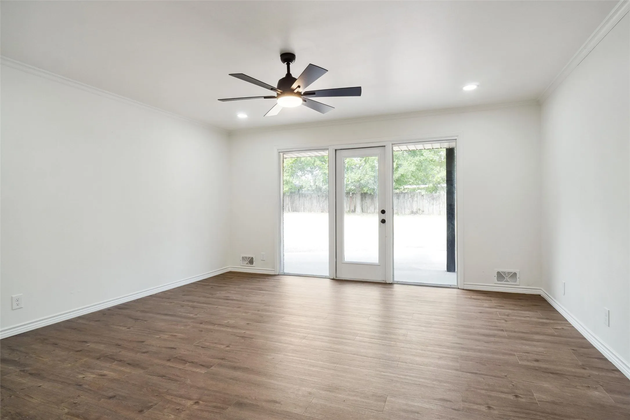 Unfurnished room featuring dark wood-type flooring, ceiling fan, and ornamental molding