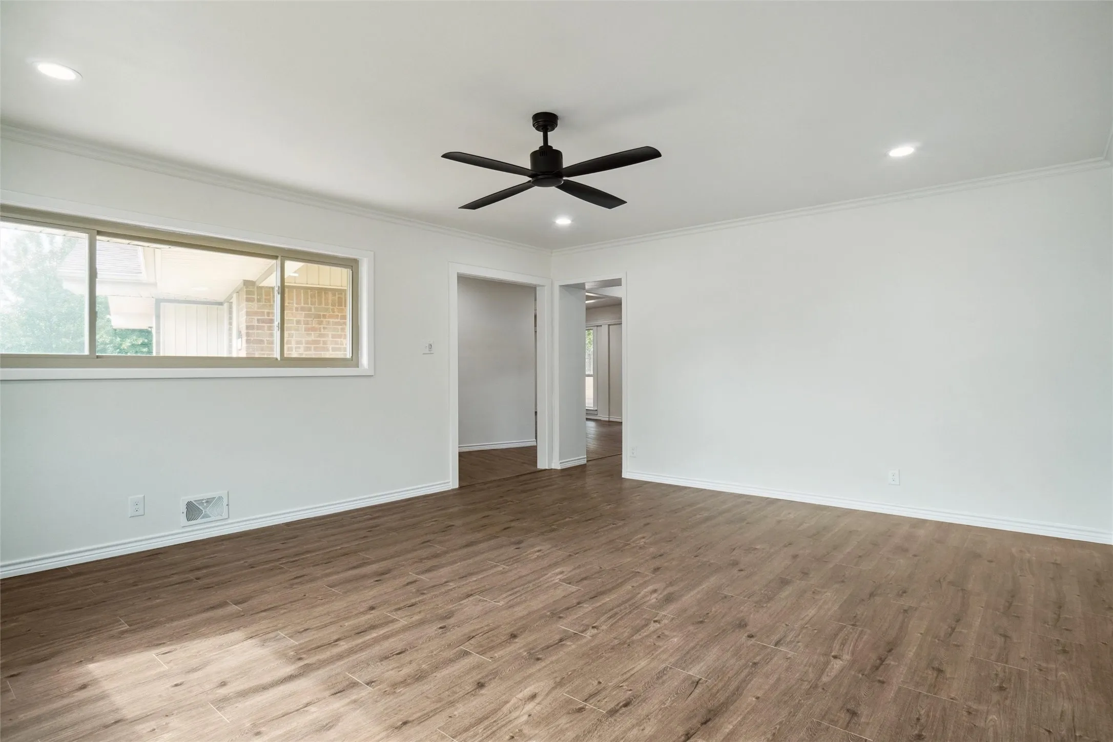 Empty room with ornamental molding, hardwood / wood-style flooring, and ceiling fan