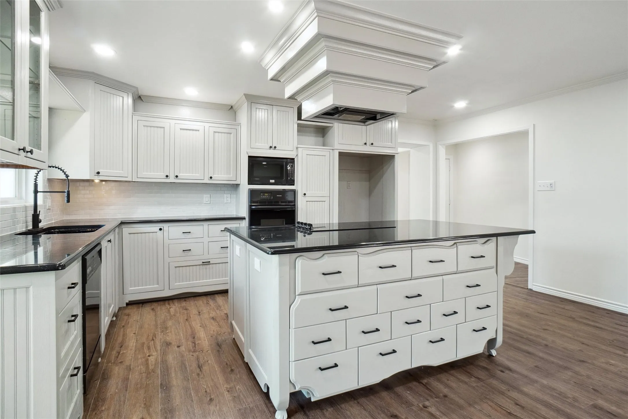 Kitchen featuring black appliances, a kitchen island, dark hardwood / wood-style flooring, and white cabinets