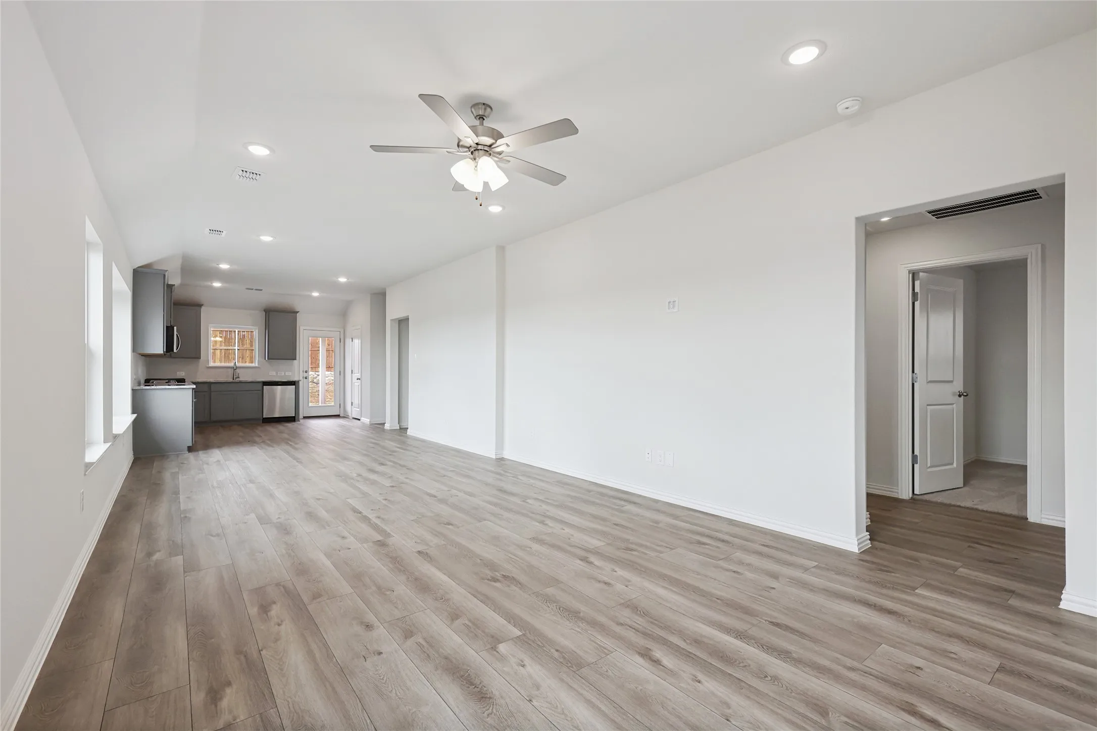 Unfurnished living room with ceiling fan, sink, and light hardwood / wood-style floors
