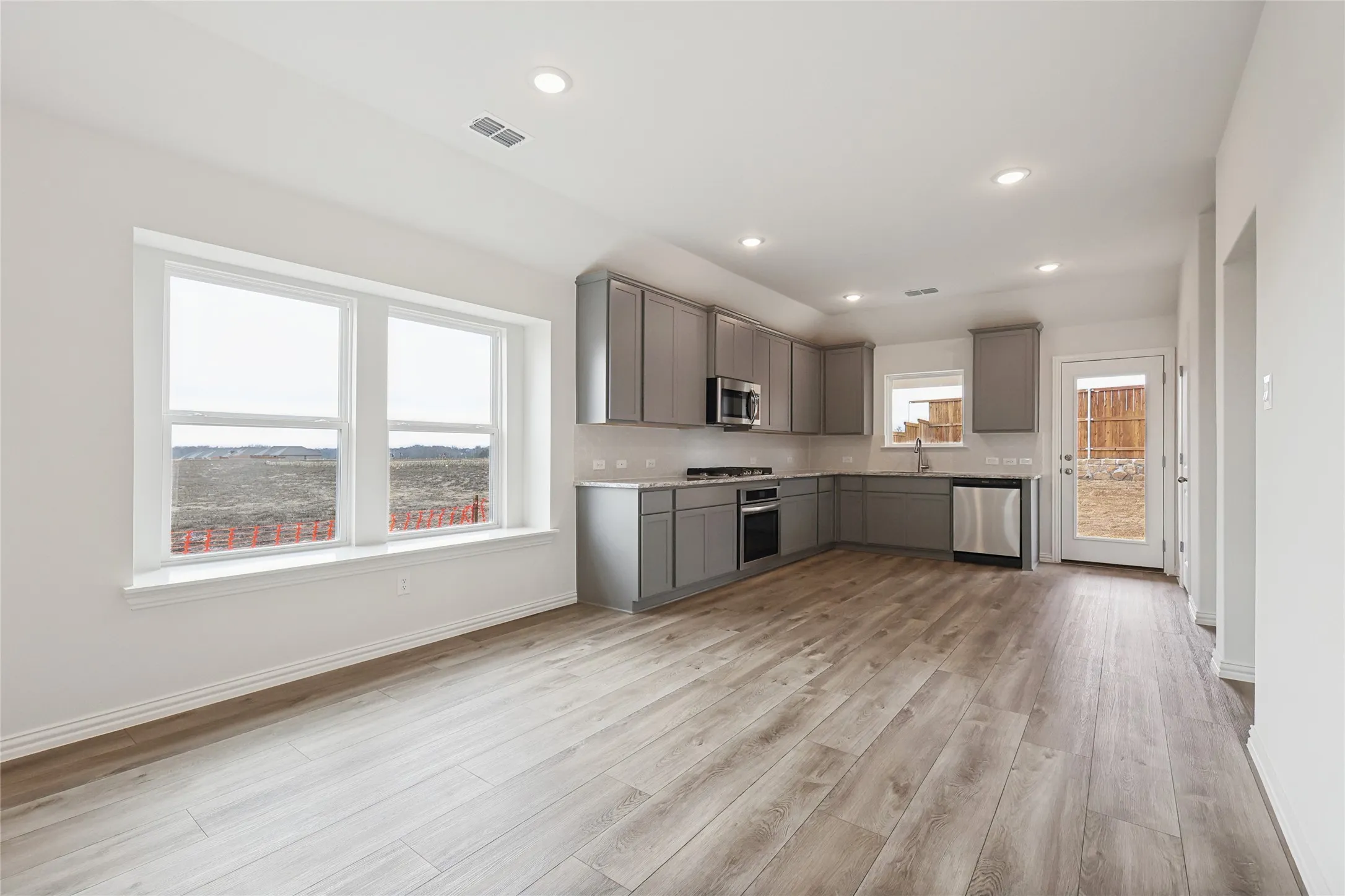 Kitchen featuring appliances with stainless steel finishes, sink, gray cabinetry, decorative backsplash, and light hardwood / wood-style floors