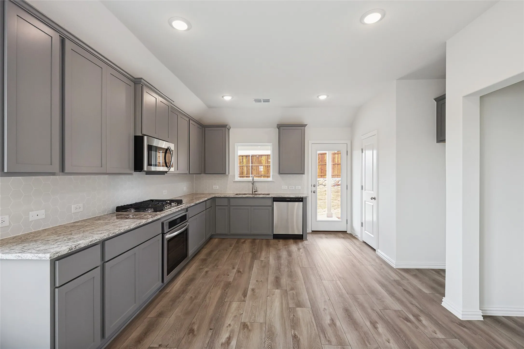 Kitchen featuring tasteful backsplash, sink, gray cabinets, and appliances with stainless steel finishes