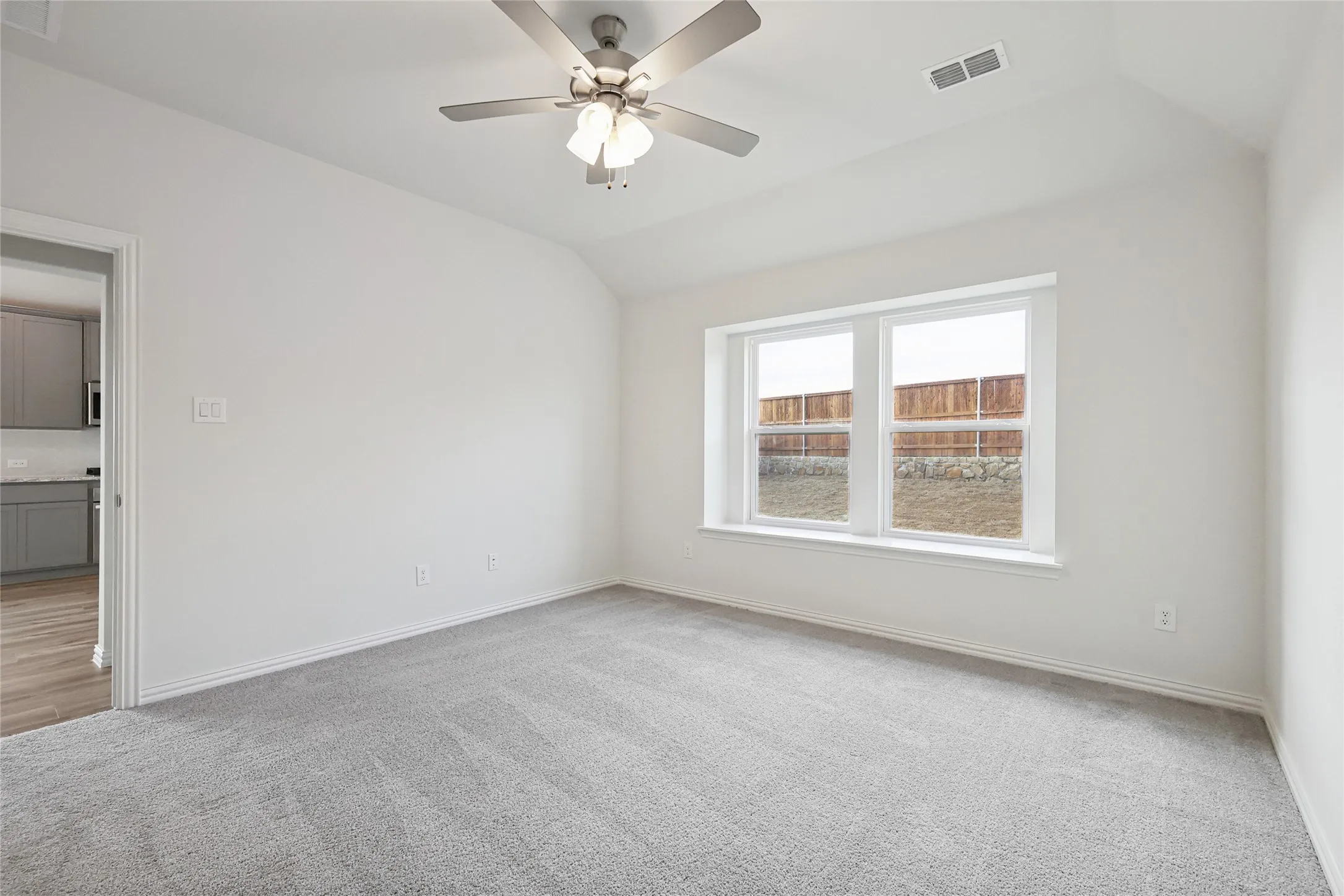 Carpeted empty room with vaulted ceiling and ceiling fan