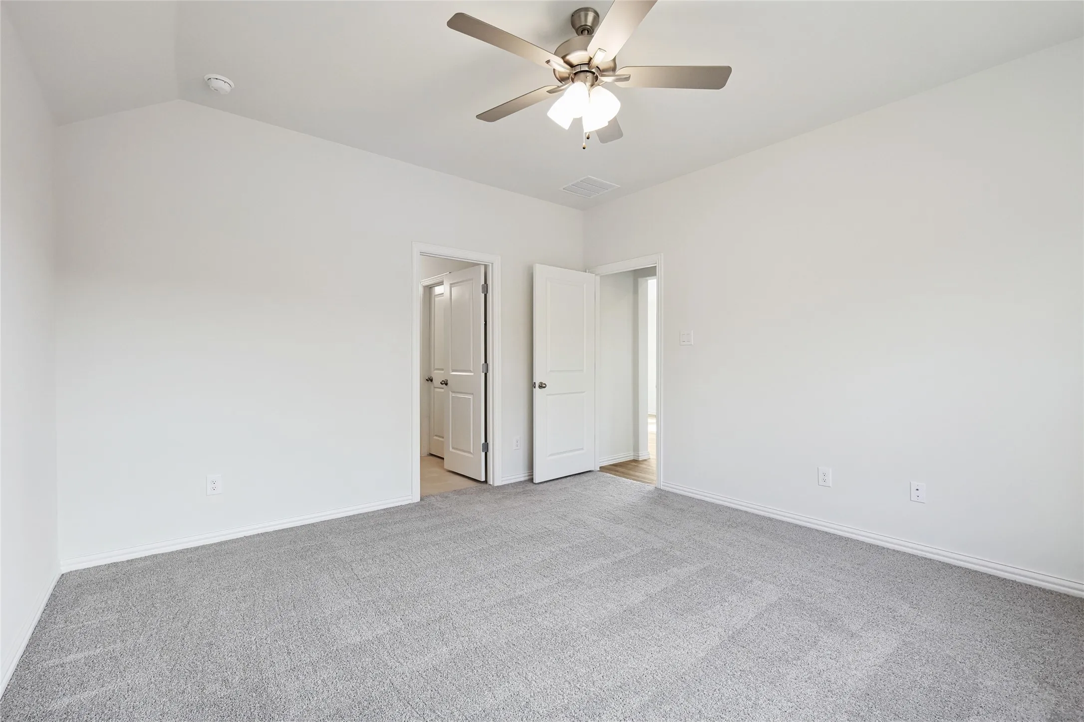 Empty room with light carpet, vaulted ceiling, and ceiling fan