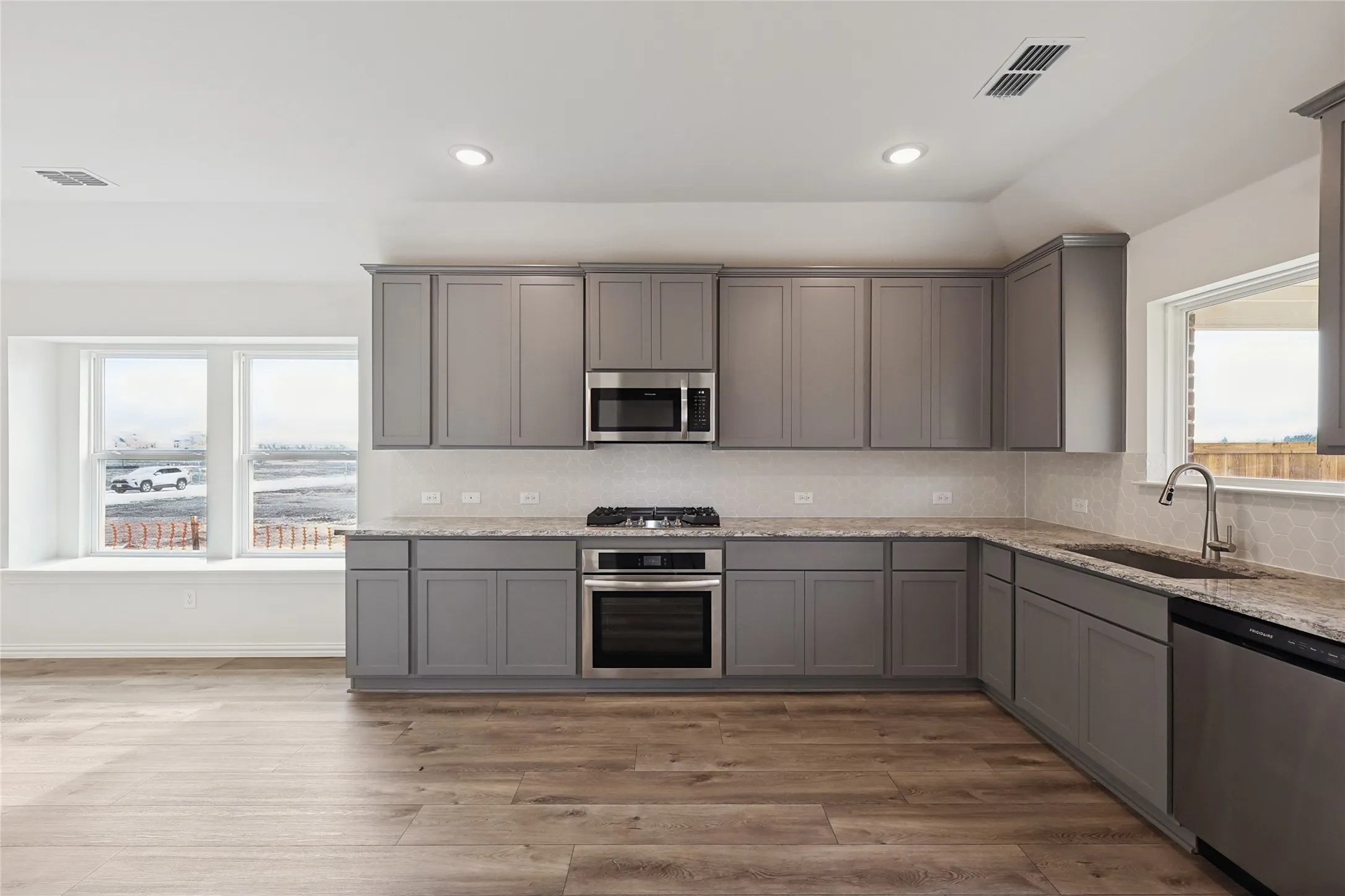 Kitchen with gray cabinetry, light stone countertops, and stainless steel appliances