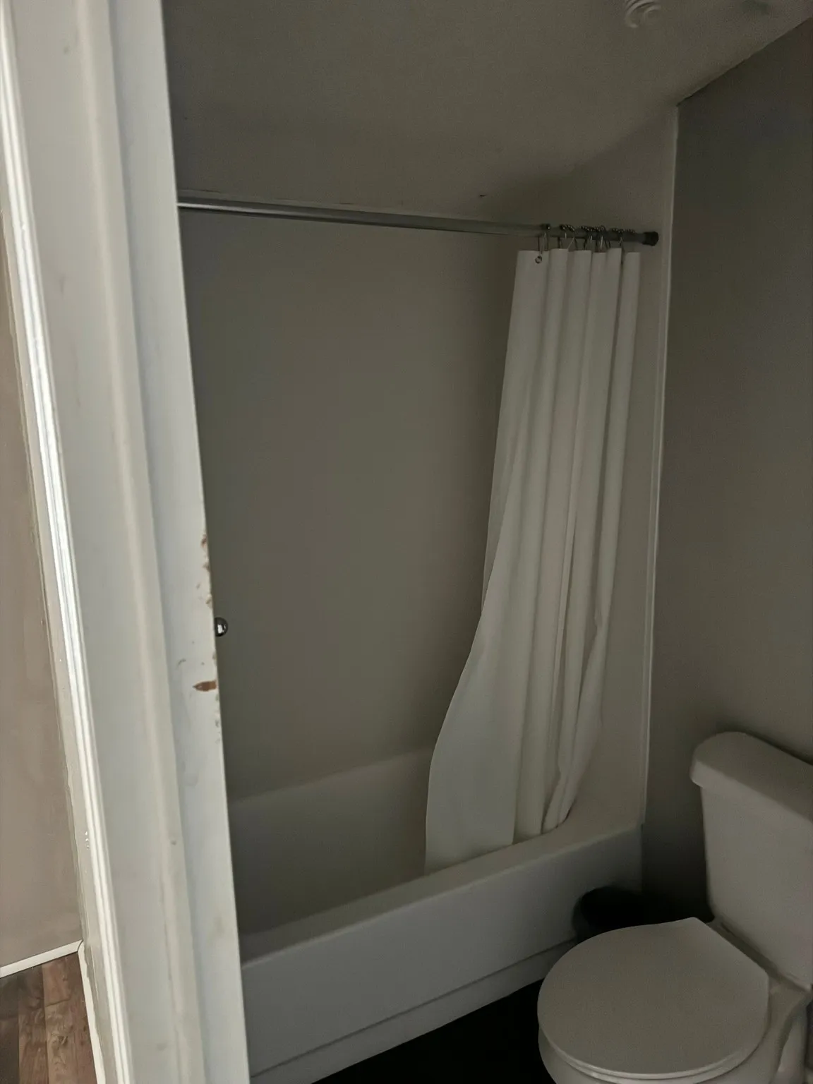 Bathroom with toilet, shower / tub combo, and hardwood / wood-style floors