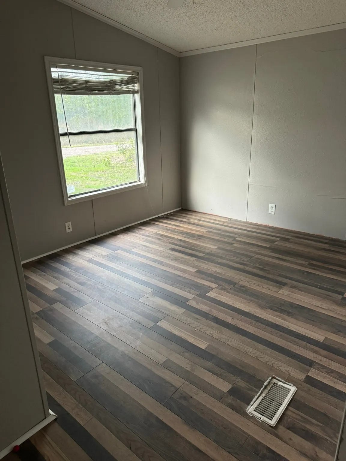 Unfurnished room with ornamental molding, dark wood-type flooring, a textured ceiling, and vaulted ceiling