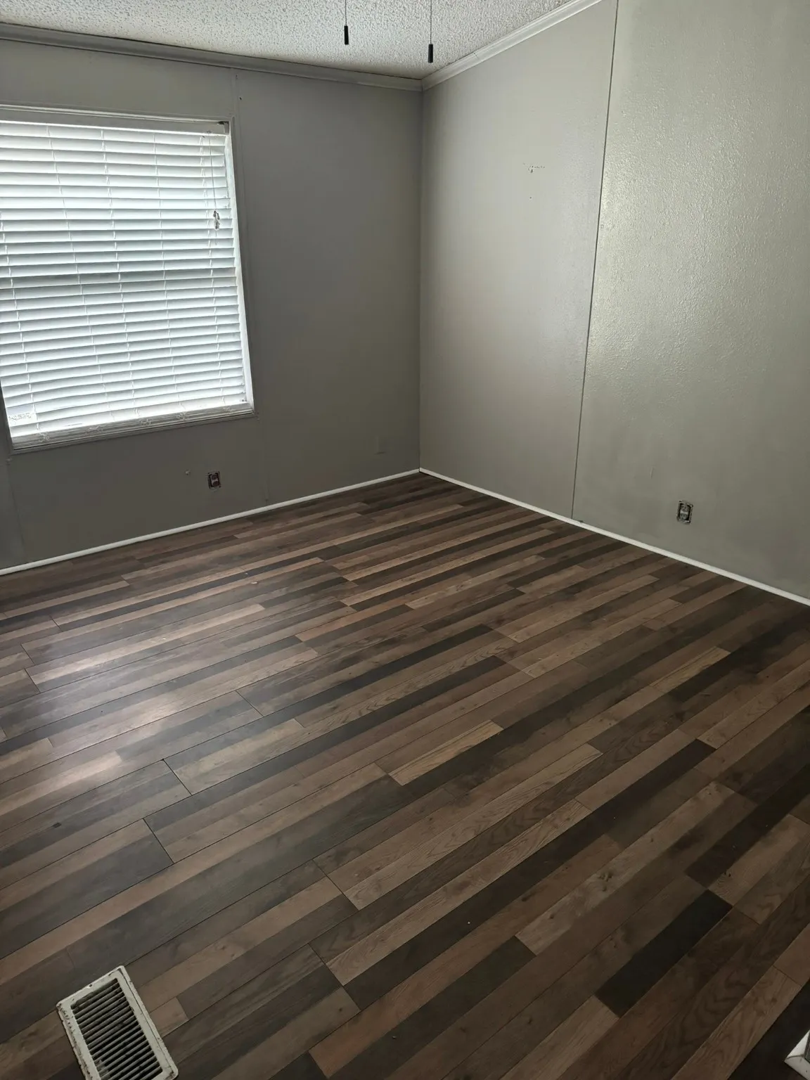 Empty room featuring dark hardwood / wood-style flooring, a textured ceiling, and crown molding