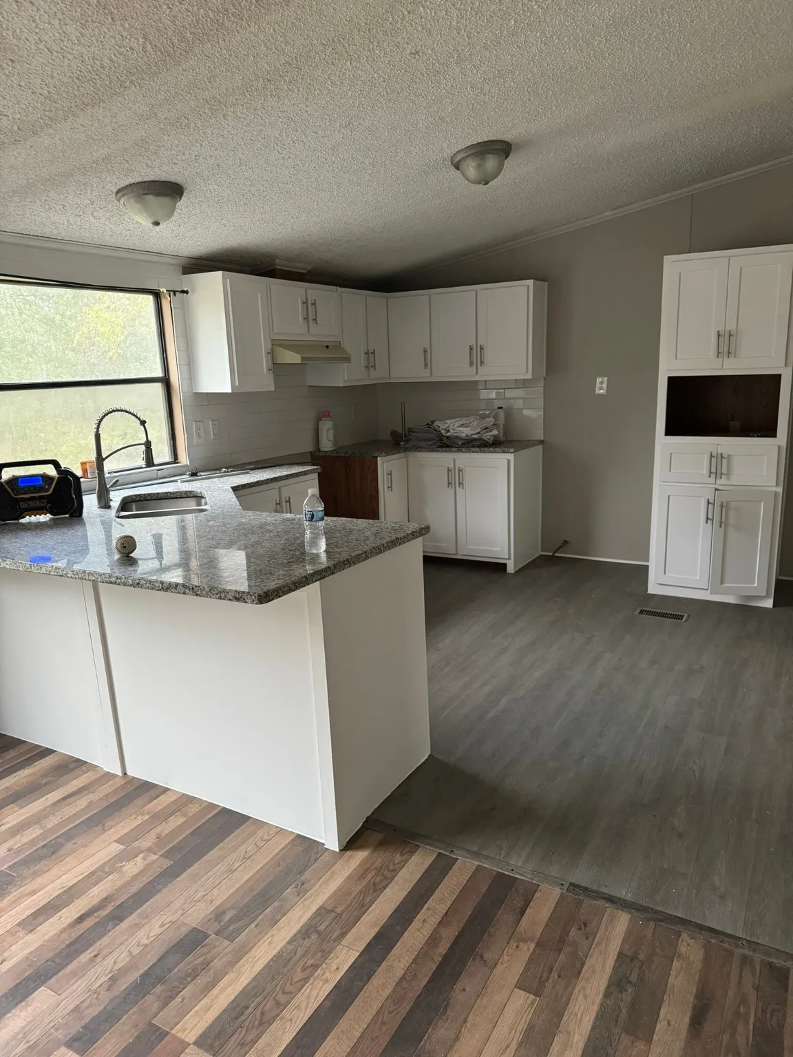 Kitchen featuring dark stone countertops, kitchen peninsula, sink, and white cabinets