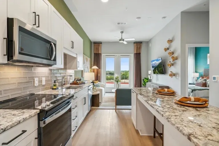 Kitchen with light stone countertops, white cabinetry, sink, light hardwood / wood-style flooring, and appliances with stainless steel finishes